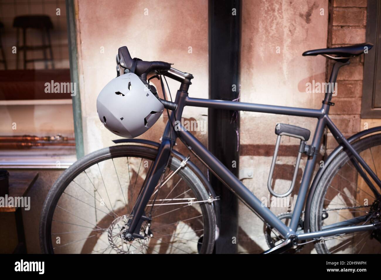 Fahrrad mit Helm gegen Wand in der Stadt geparkt Stockfoto