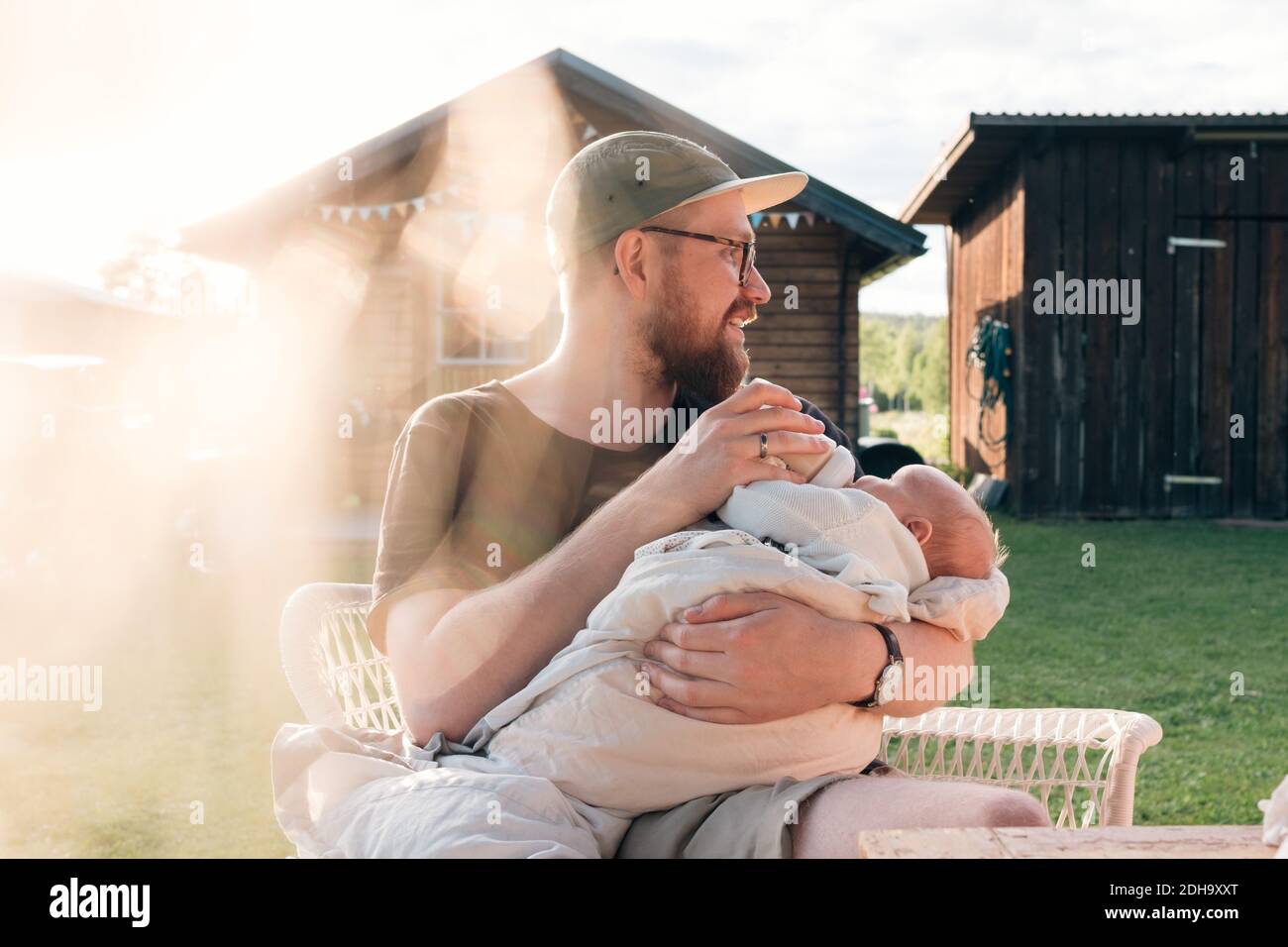 Mittlerer Erwachsener Mann hält Baby Junge, während draußen sitzen Stockfoto Mittlerer Erwachsener Mann hält Baby Junge, während draußen sitzen Stockfoto