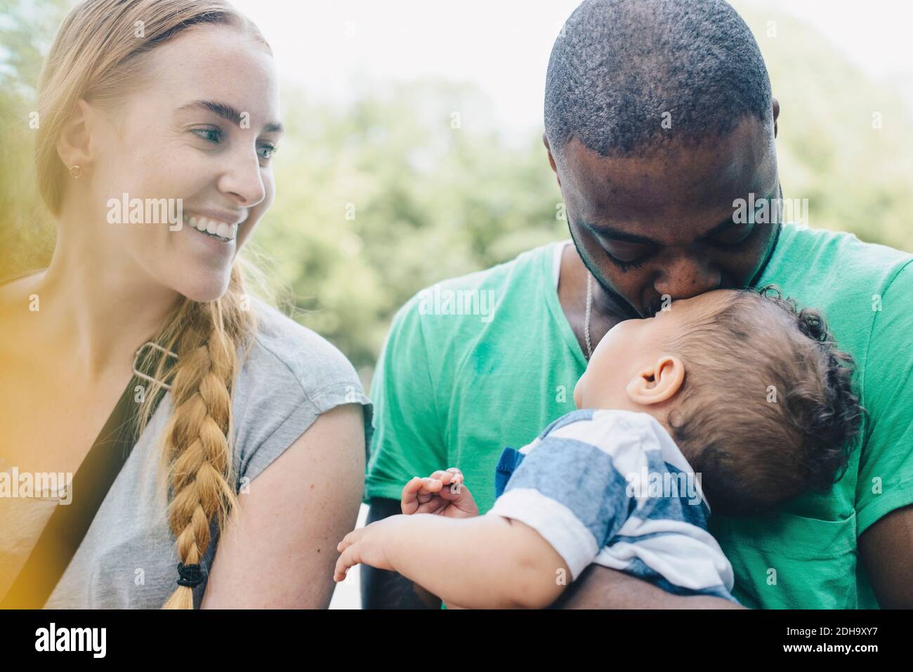 Nahaufnahme einer lächelnden Frau, die den Mann betrachtet, der den Sohn küsst Stockfoto