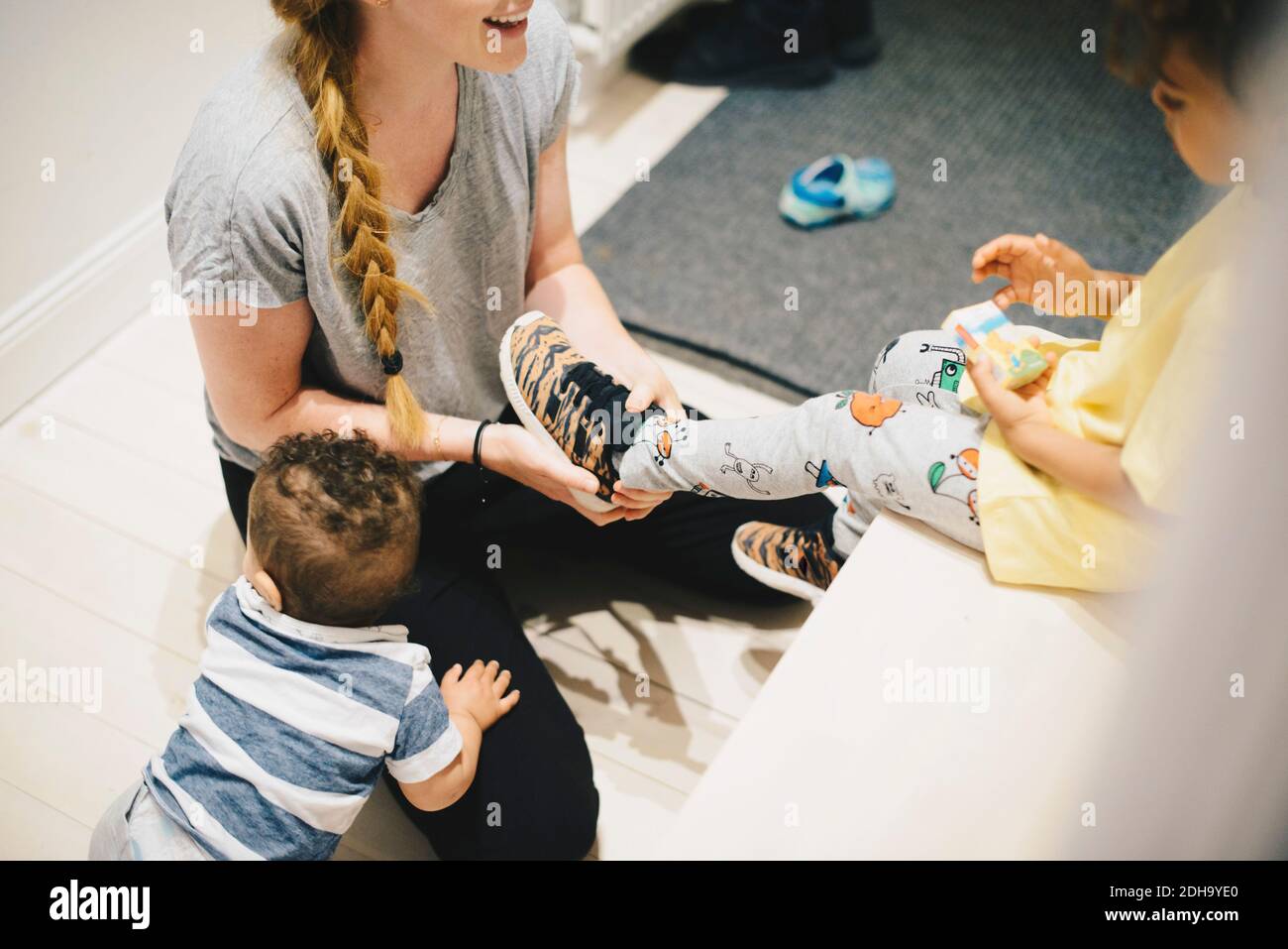 Mutter mit Kleinkind, der die Schuhe des Sohnes zu Hause anzieht Stockfoto