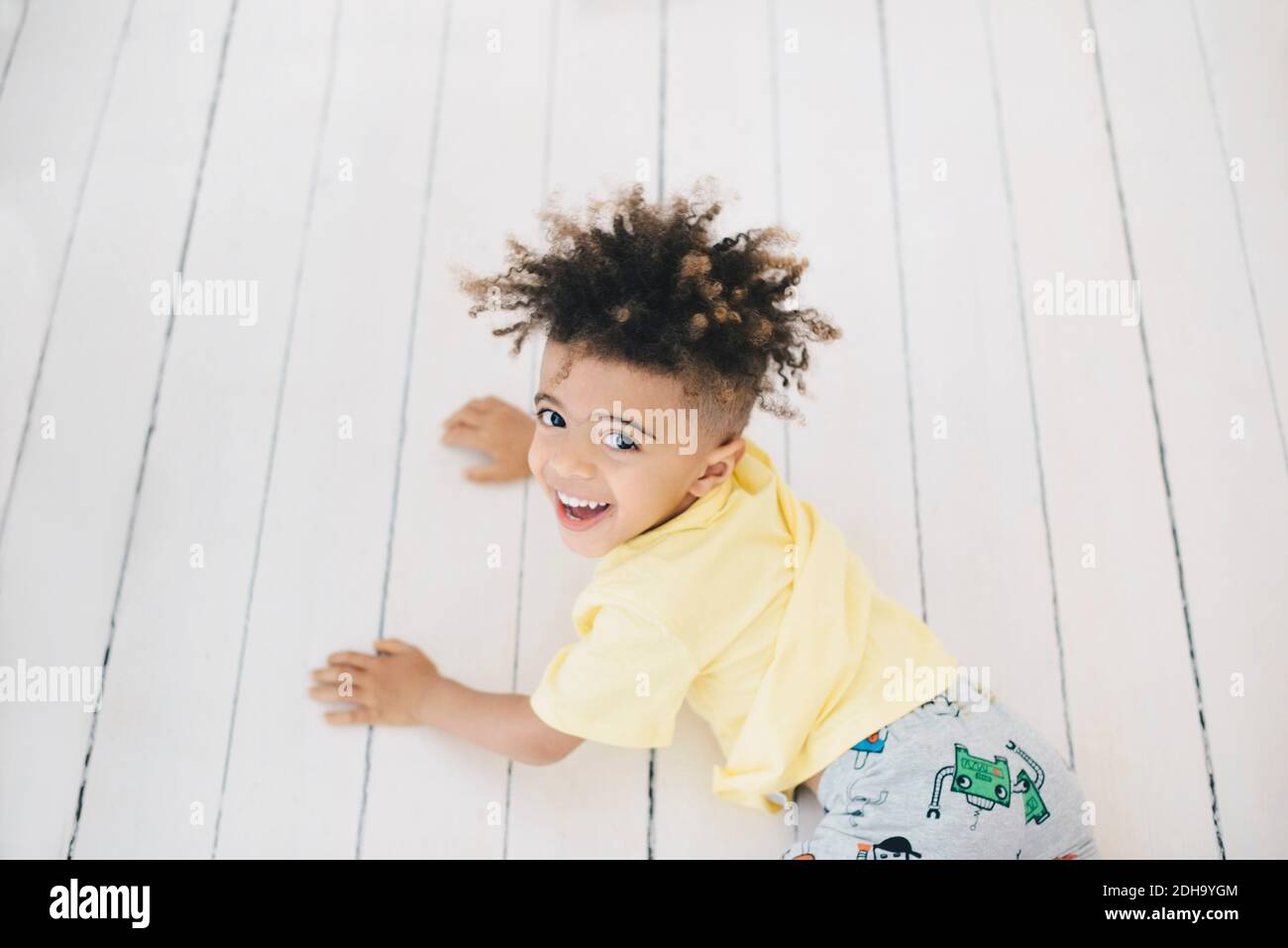 Hochwinkel-Porträt des Jungen auf Hartholzboden liegen bei Zu Hause Stockfoto