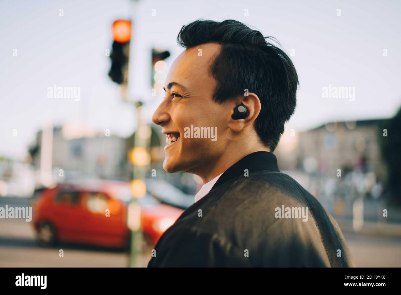 Ein fröhlicher Mann, der in der Stadt mit in-Ear-Kopfhörern unterwegs ist Stockfoto