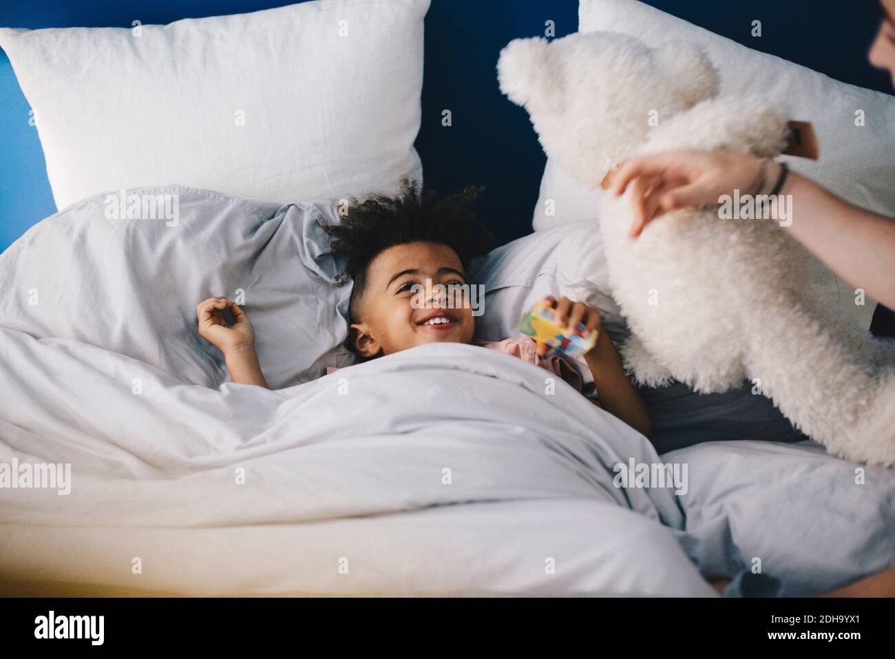 Lächelnder Junge, der Mutter ansieht, während er auf dem Bett liegt Zu Hause Stockfoto