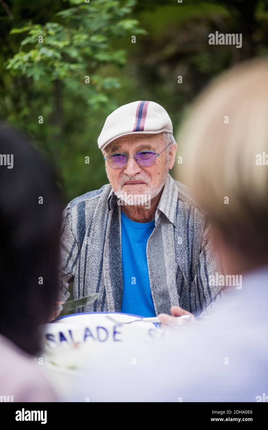 Reifes Paar sitzt vor einem älteren Mann im Rücken Hof Stockfoto