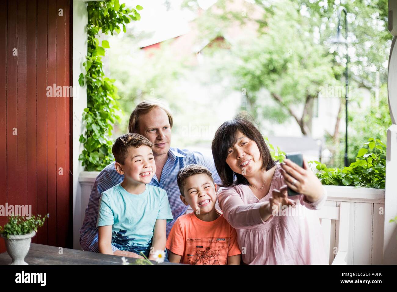 Mutter nimmt Selfie mit Familie auf der Veranda Stockfoto