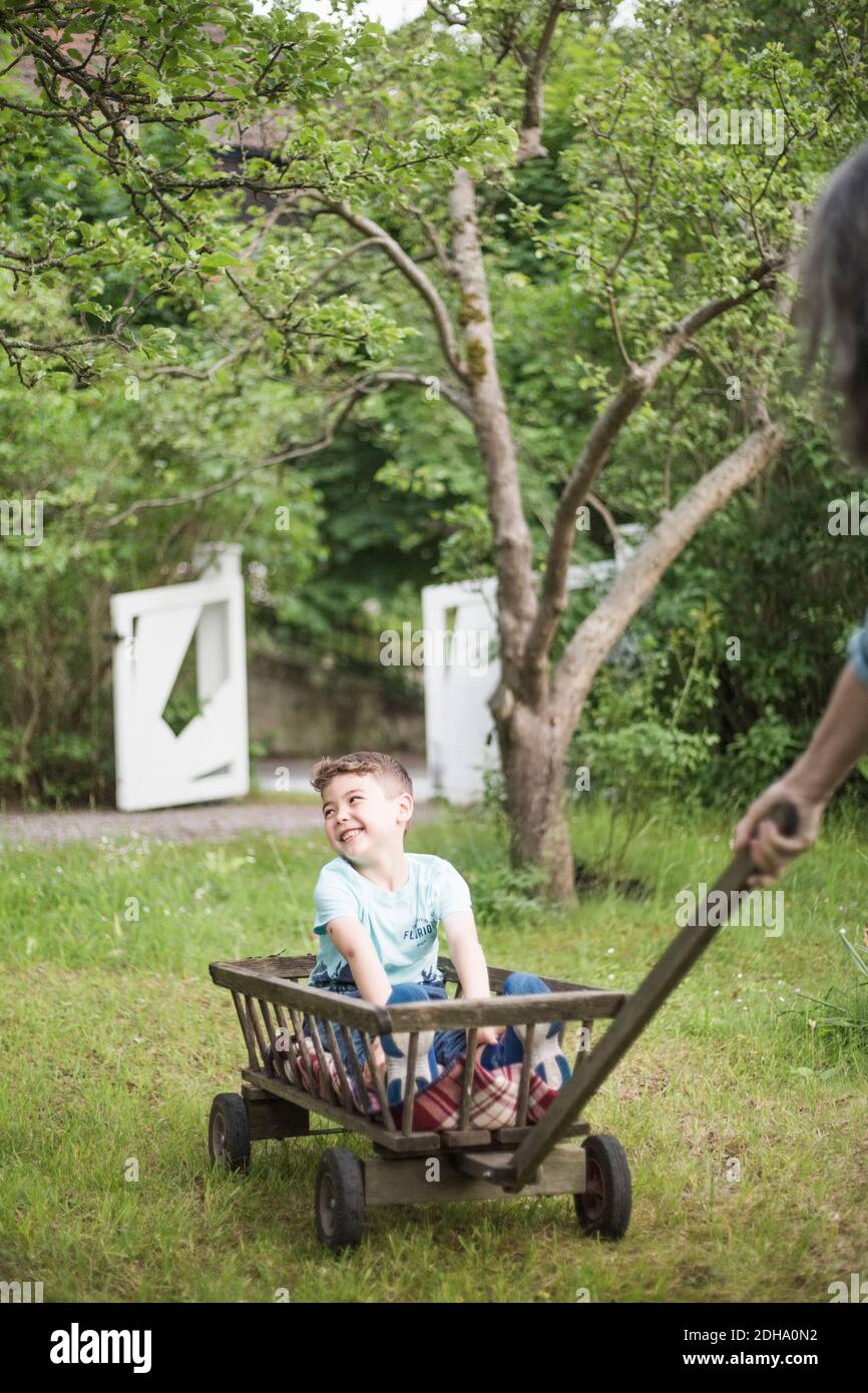 Großmutter zieht Wagen mit lächelndem Jungen im Hinterhof Stockfoto