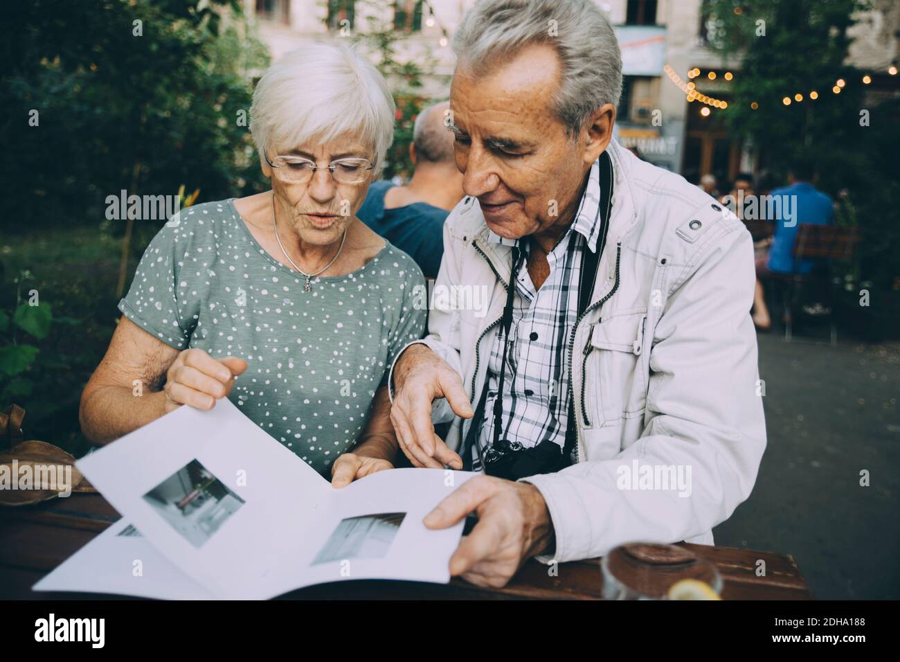 Ältere Mann und Frau Touristen Blick auf Bilder im Buch Beim Sitzen im Restaurant Stockfoto