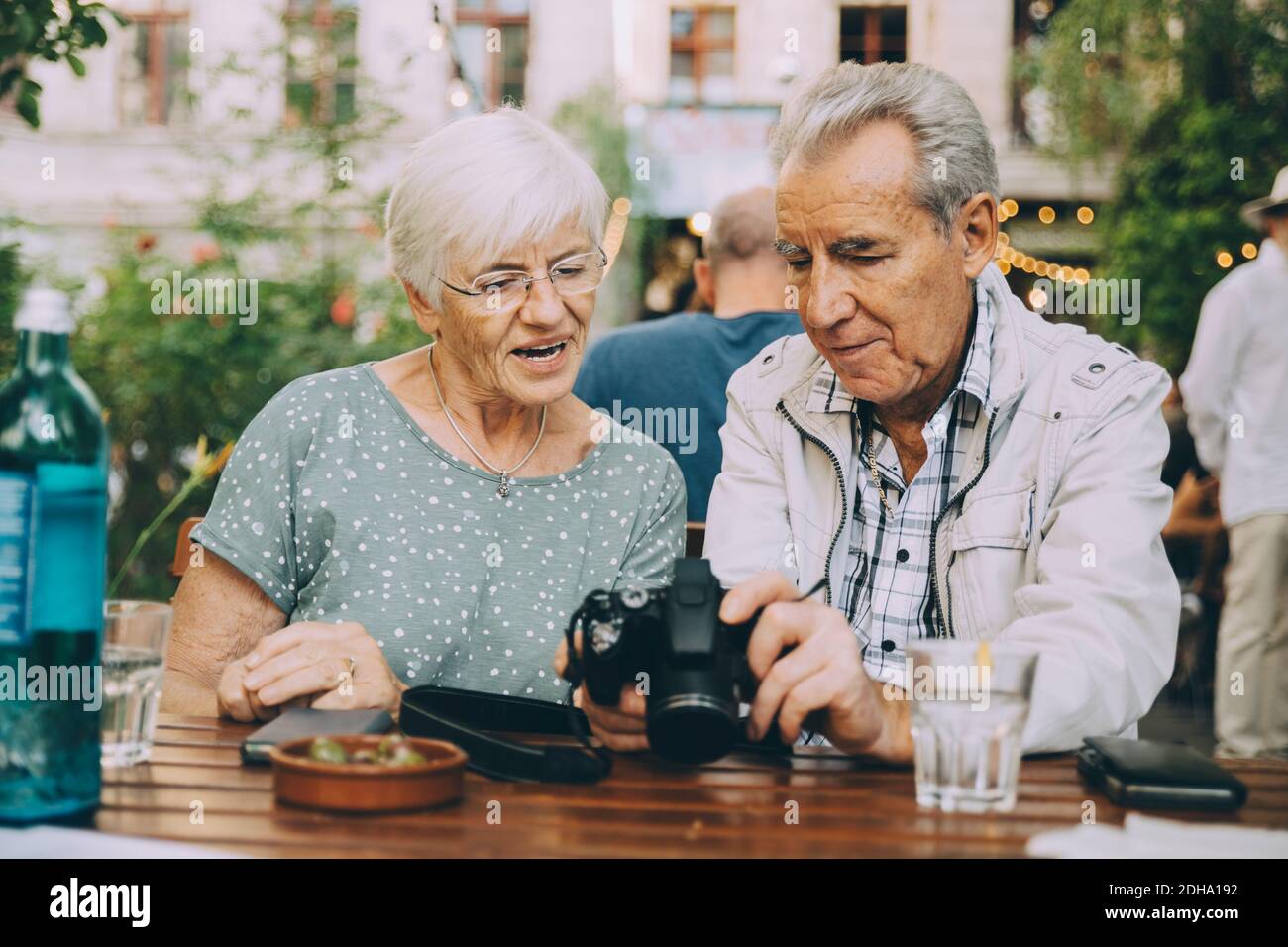 Älterer Mann, der der Frau die Kamera zeigt, während er im Restaurant sitzt In der Stadt Stockfoto