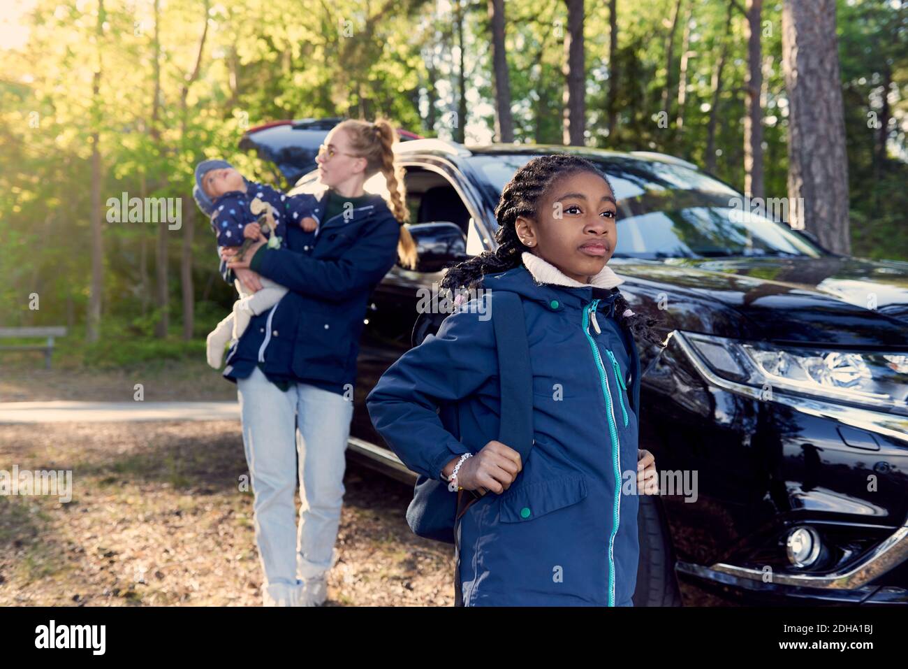 Mädchen steht gegen Mutter trägt Baby Junge mit dem Auto mitten Bäume Stockfoto Mädchen steht gegen Mutter trägt Baby Junge mit dem Auto mitten Bäume Stockfoto