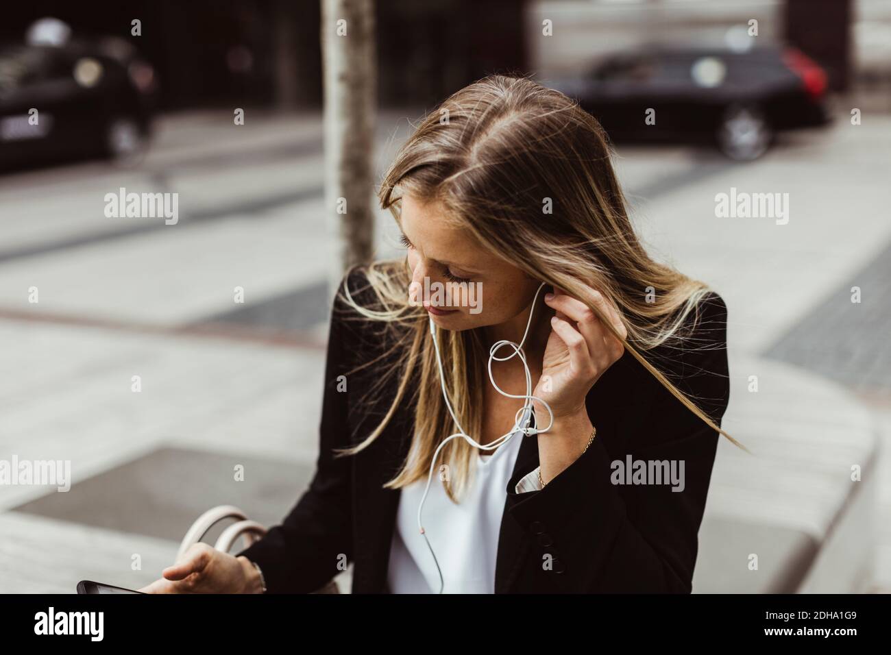 Geschäftsfrau mit in-Ear-Kopfhörern im Freien Stockfoto