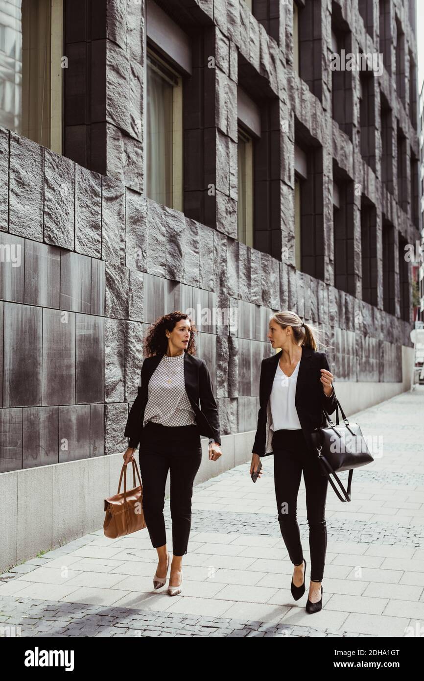 Geschäftsfrauen sprechen beim Gehen durch Gebäude Stockfoto