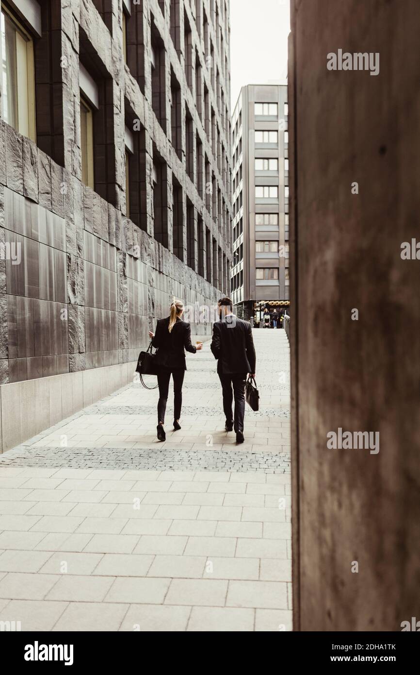 Rückansicht von Geschäftsleuten, die beim Gang durch das Gebäude reden In der Stadt Stockfoto