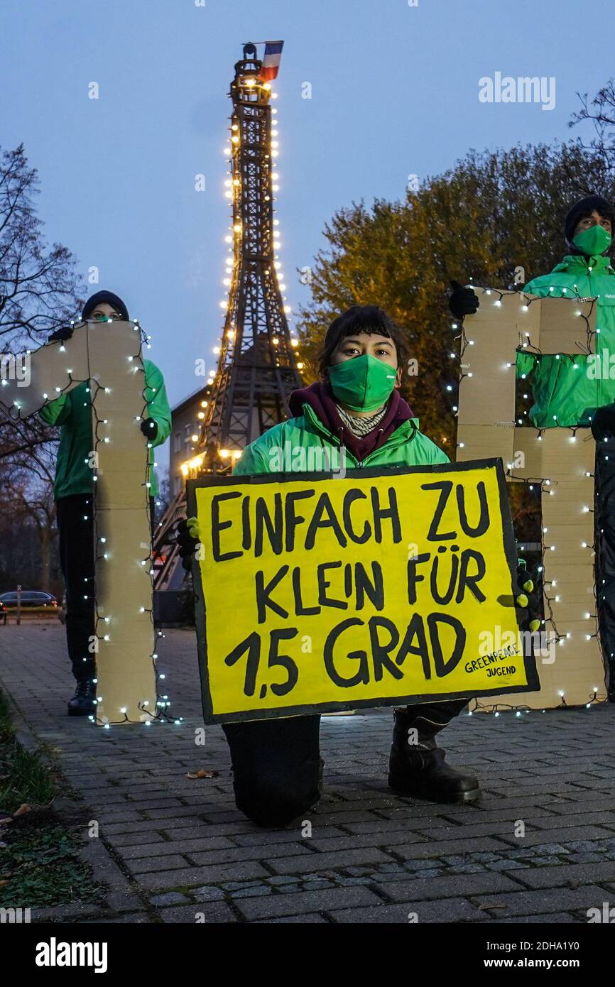 Berlin, Deutschland. Dezember 2020. Mitglieder der Greenpeace-Jugend halten während einer Lichtaktion ein Transparent mit den Worten "zu klein für 1.5 Grad" und der Zahl "1.5" vor dem Miniatur-Eiffelturm im Centre Francaise. Die jungen Aktivisten fordern mehr Anstrengungen, um den Temperaturanstieg auf 1.5 Grad zu begrenzen - wie es die Pariser Klimakonvention anstrebt. Quelle: Jörg Carstensen/dpa/Alamy Live News Stockfoto