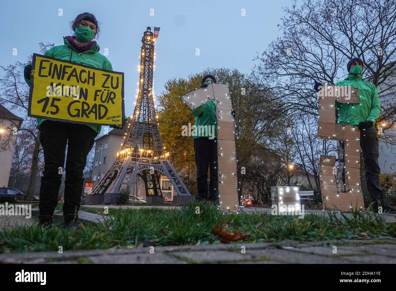 Berlin, Deutschland. Dezember 2020. Mitglieder der Greenpeace-Jugend halten während einer Lichtaktion ein Transparent mit den Worten "zu klein für 1.5 Grad" und der Zahl "1.5" vor dem Miniatur-Eiffelturm im Centre Francaise. Die jungen Aktivisten fordern mehr Anstrengungen, um den Temperaturanstieg auf 1.5 Grad zu begrenzen - wie es die Pariser Klimakonvention anstrebt. Quelle: Jörg Carstensen/dpa/Alamy Live News Stockfoto