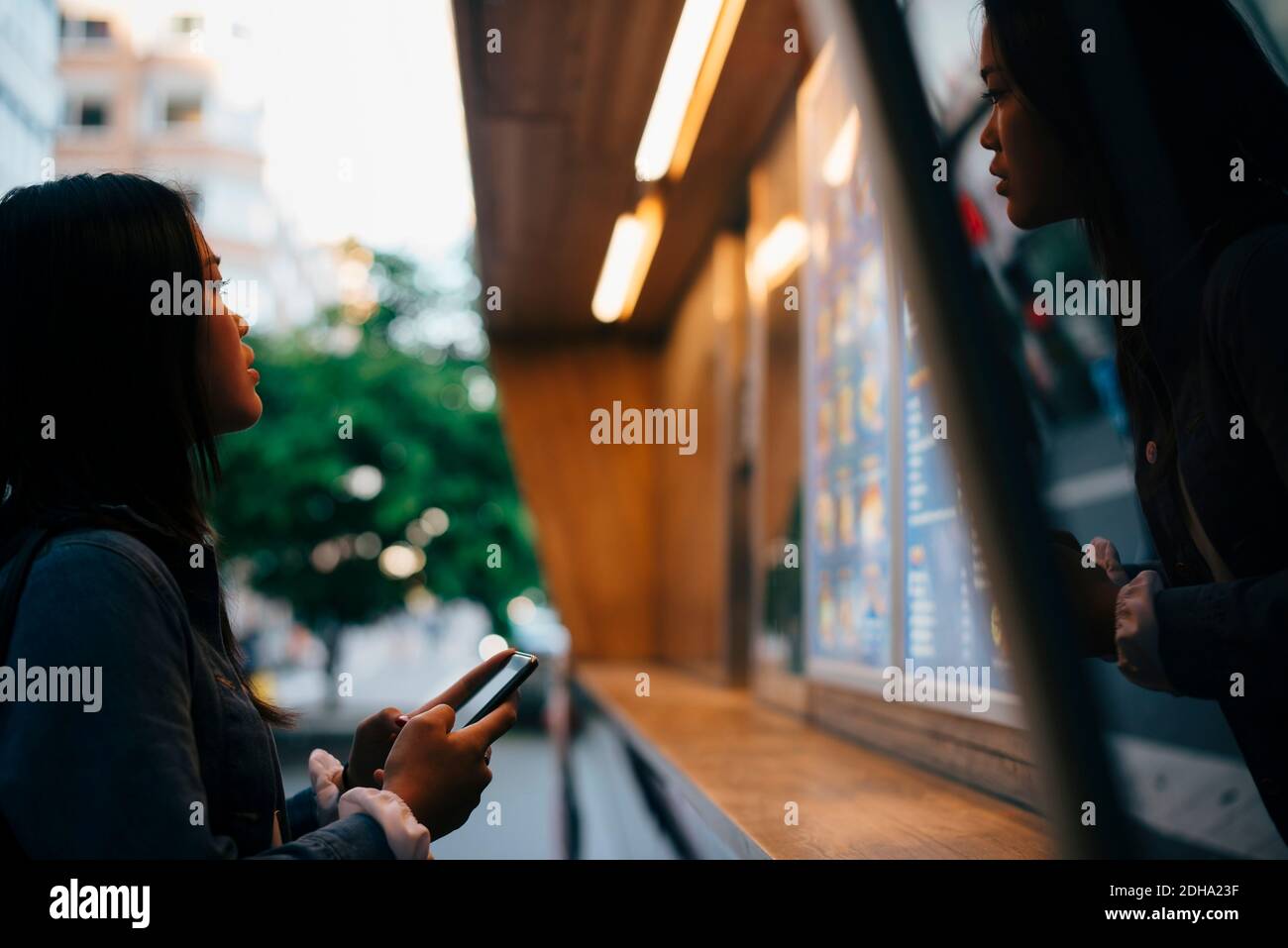 Seitenansicht eines Teenagers, das mit dem Mobiltelefon stand Blick auf Menü Stockfoto