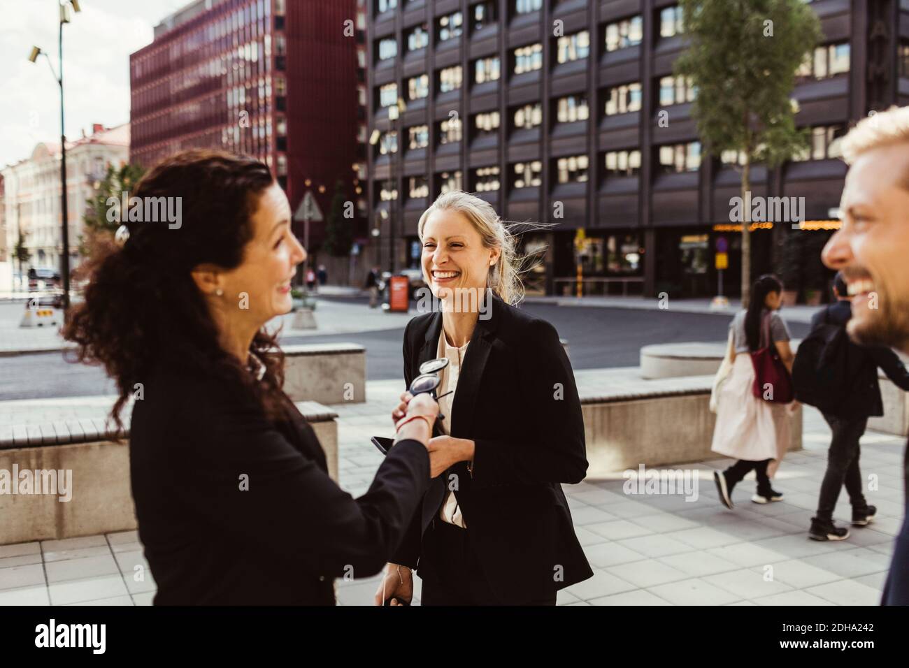 Unternehmerin lächelt mit Kollegen, während sie im Freien steht Stockfoto