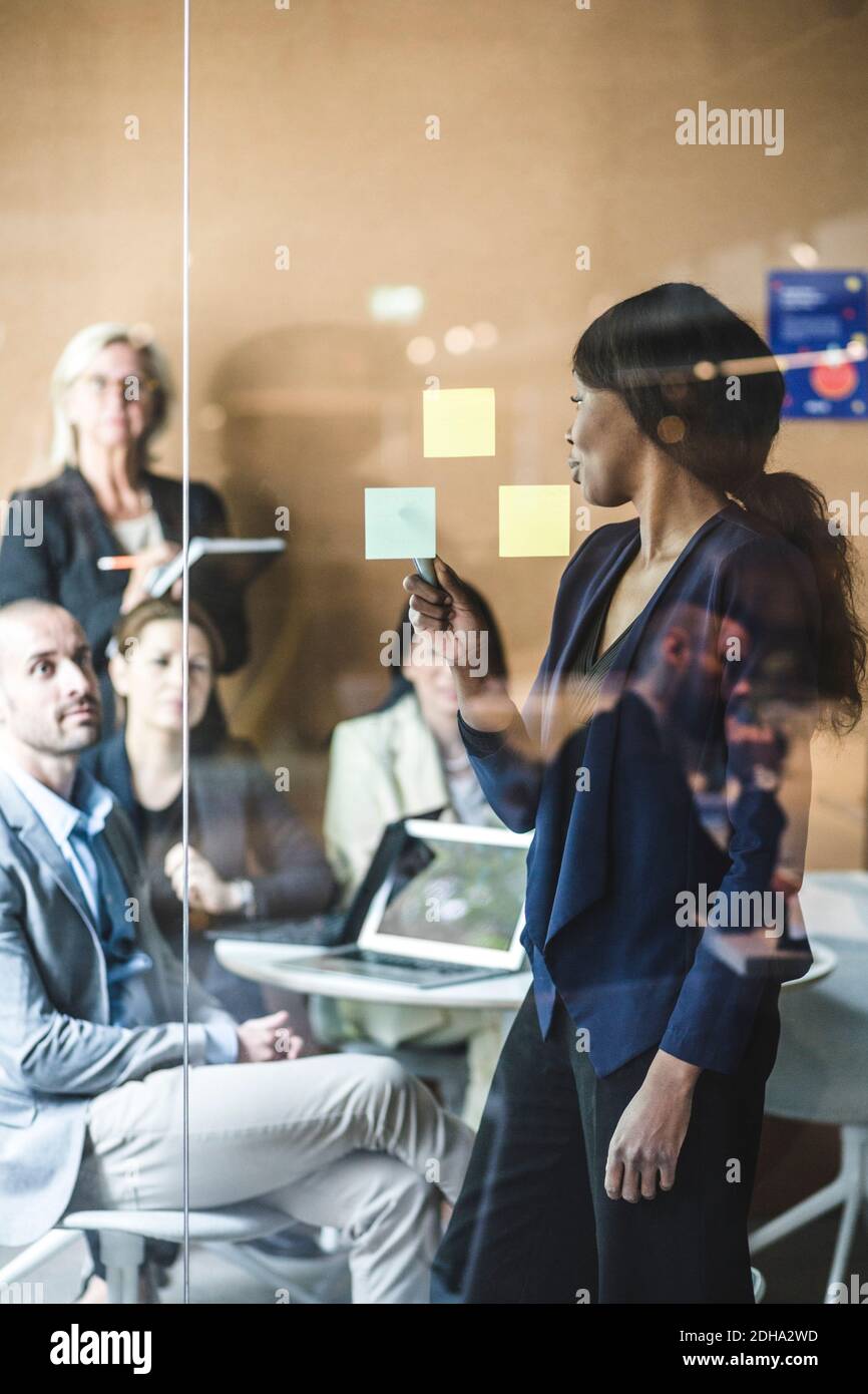 Geschäftsfrau erklärt den Mitarbeitern im Sitzungssaal während der Besprechung Notizen Stockfoto