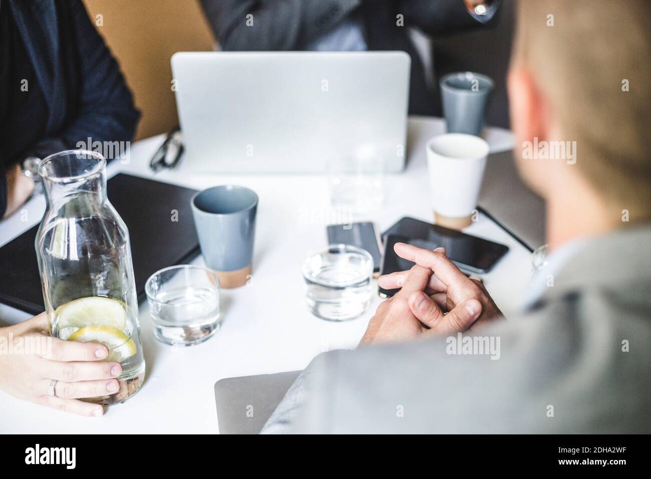 Mittelteil von Geschäftskollegen, die während des Büros im Vorstandszimmer sitzen Besprechung Stockfoto