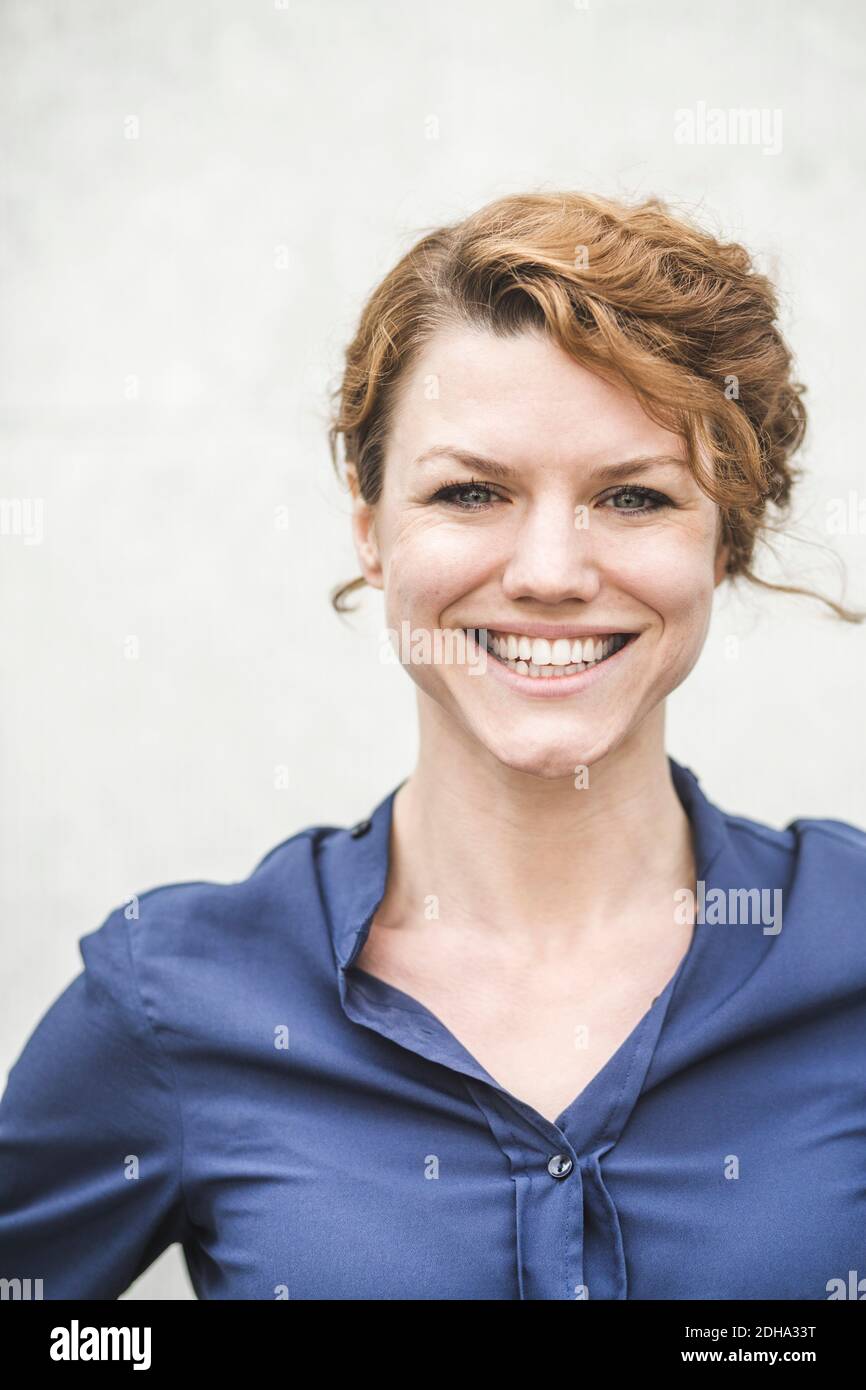 Porträt einer lächelnden Unternehmerin, die gegen die Wand steht Stockfoto