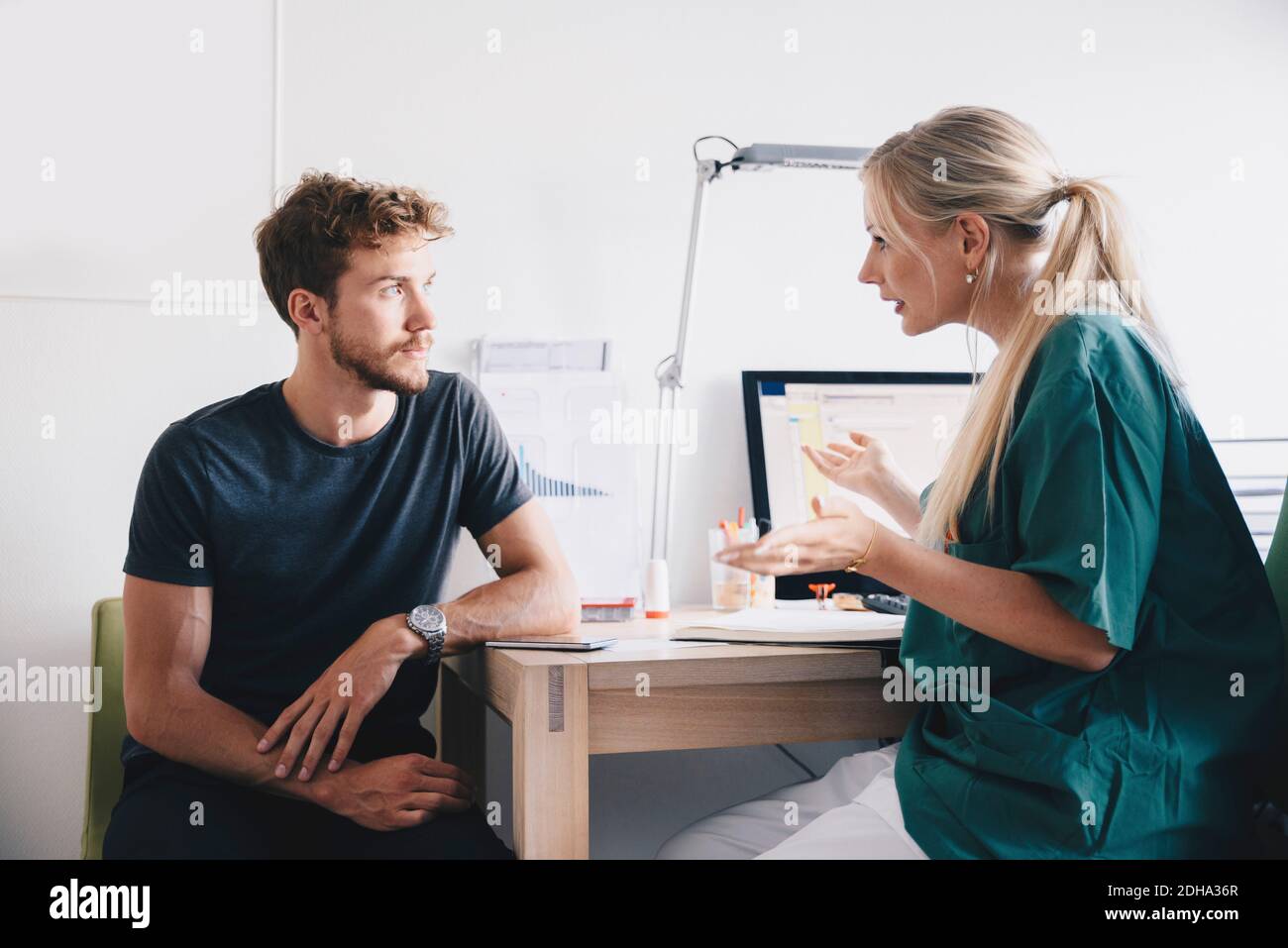 Krankenschwester erklärt jungen männlichen Patienten im Büro in Krankenhaus Stockfoto