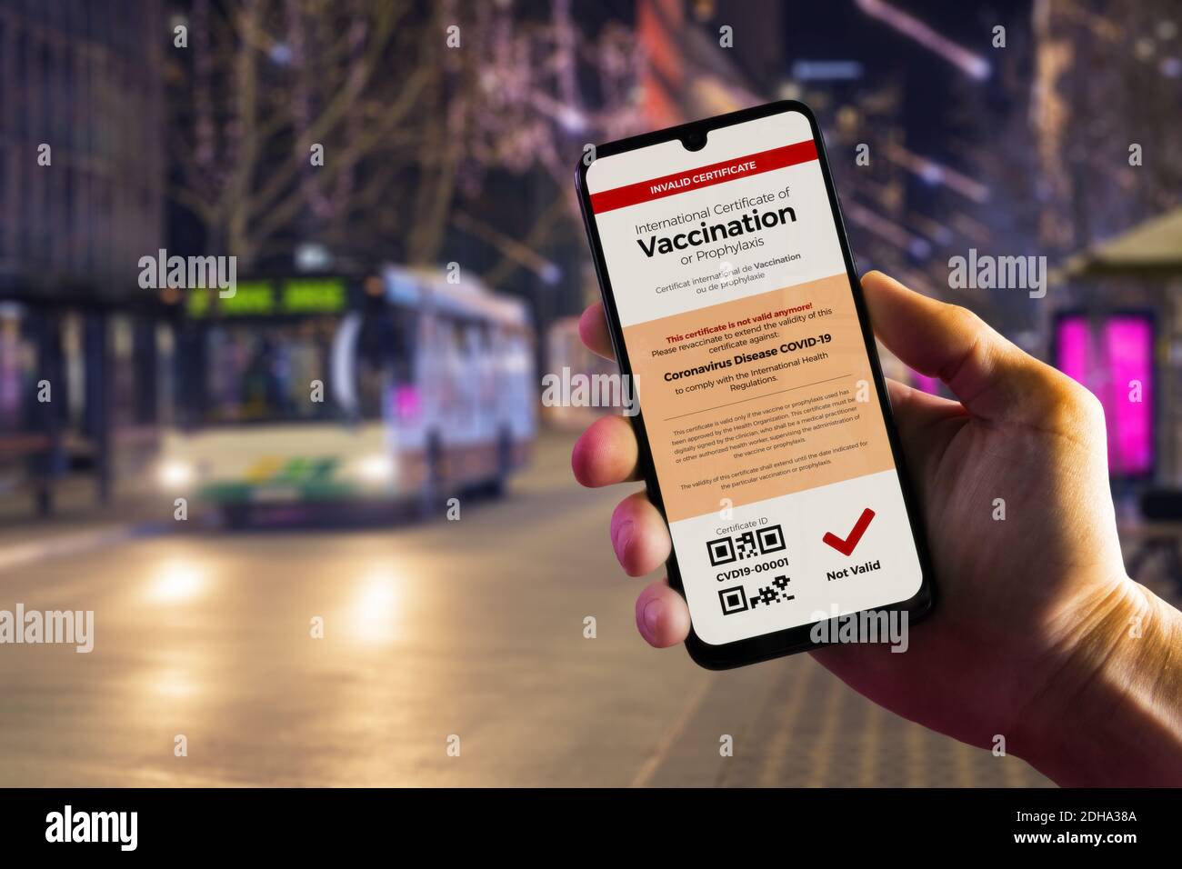 Smartphone zeigt einen ungültigen digitalen Impfpass für COVID-19 in Männerhand, Innenstadt und Stadtbus im Hintergrund. Impfung, Immunisierung Stockfoto