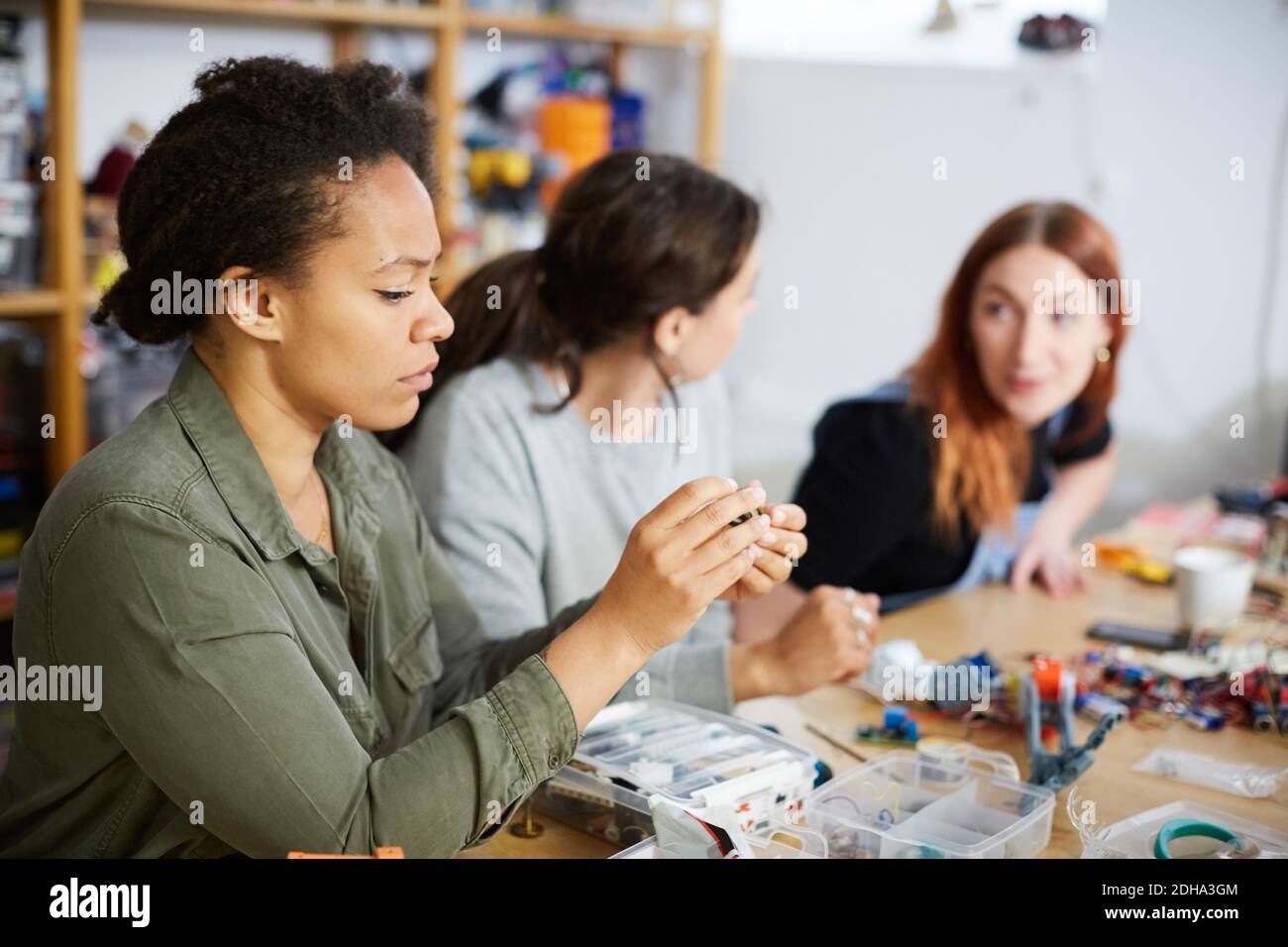 Mittlere Erwachsene Technikerin mit Ausrüstung von jungen weiblichen Kollegen bei Werkstatt Stockfoto