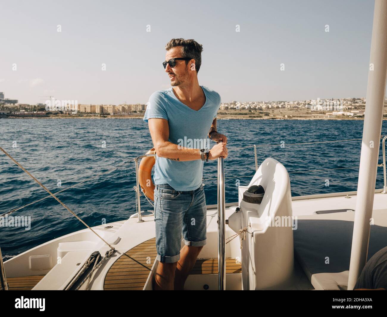 Reifer Mann trägt Sonnenbrille Segelboot im Meer gegen Himmel Stockfoto