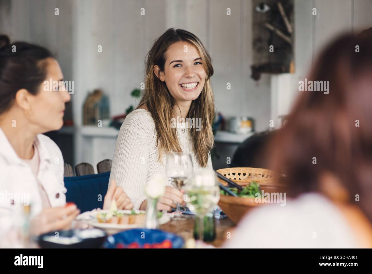 Glückliche junge Freundinnen genießen am Esstisch während des Mittagessens Party Stockfoto