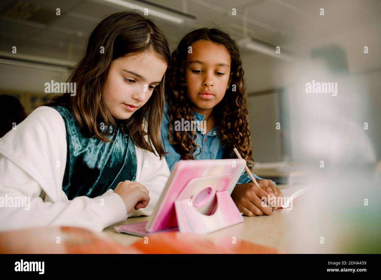 Schülerinnen mit digitalem Tablet am Tisch im Klassenzimmer Stockfoto