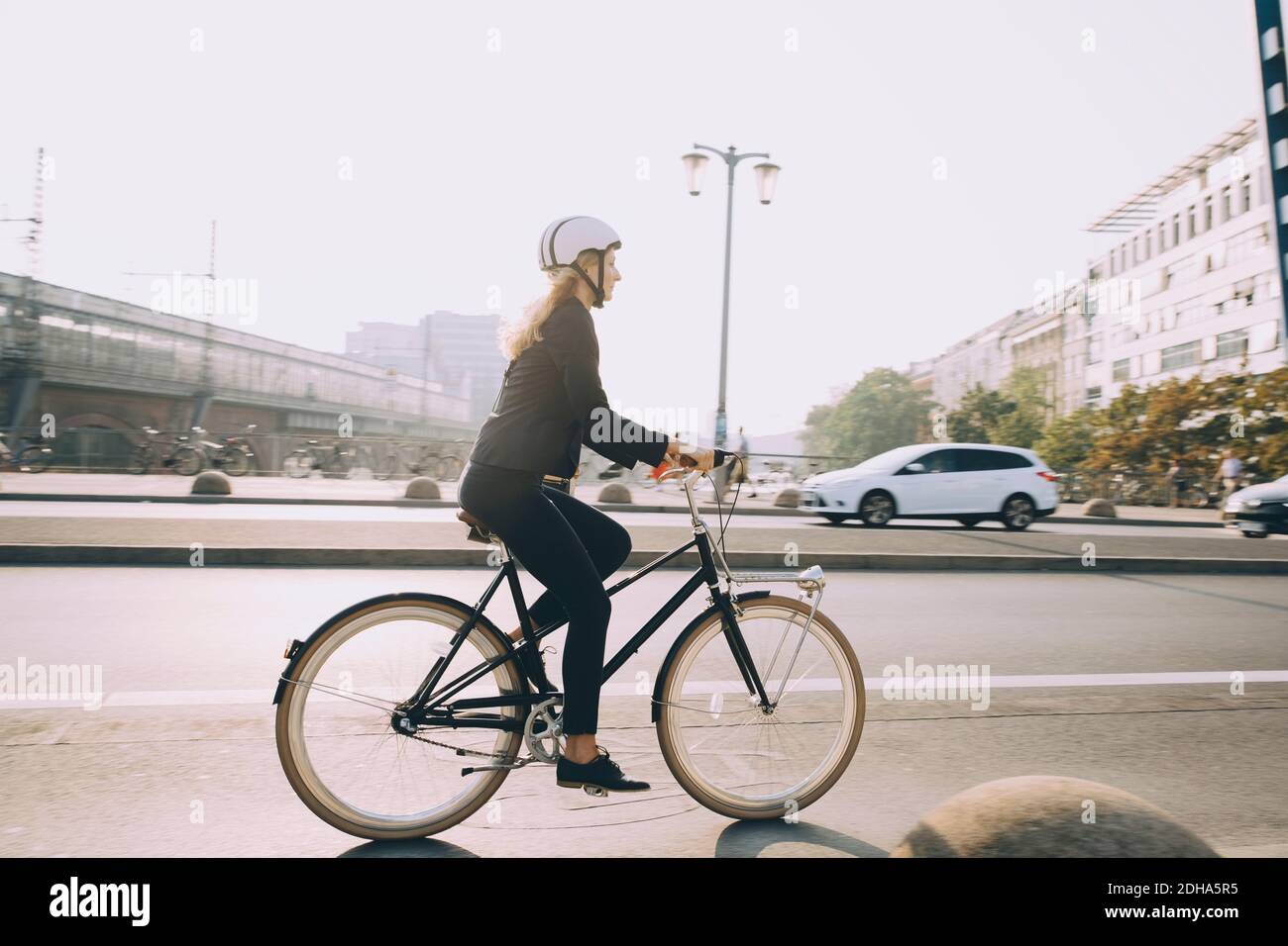 Volle Länge der weiblichen Executive trägt Helm Fahrrad fahren auf Straße in der Stadt Stockfoto