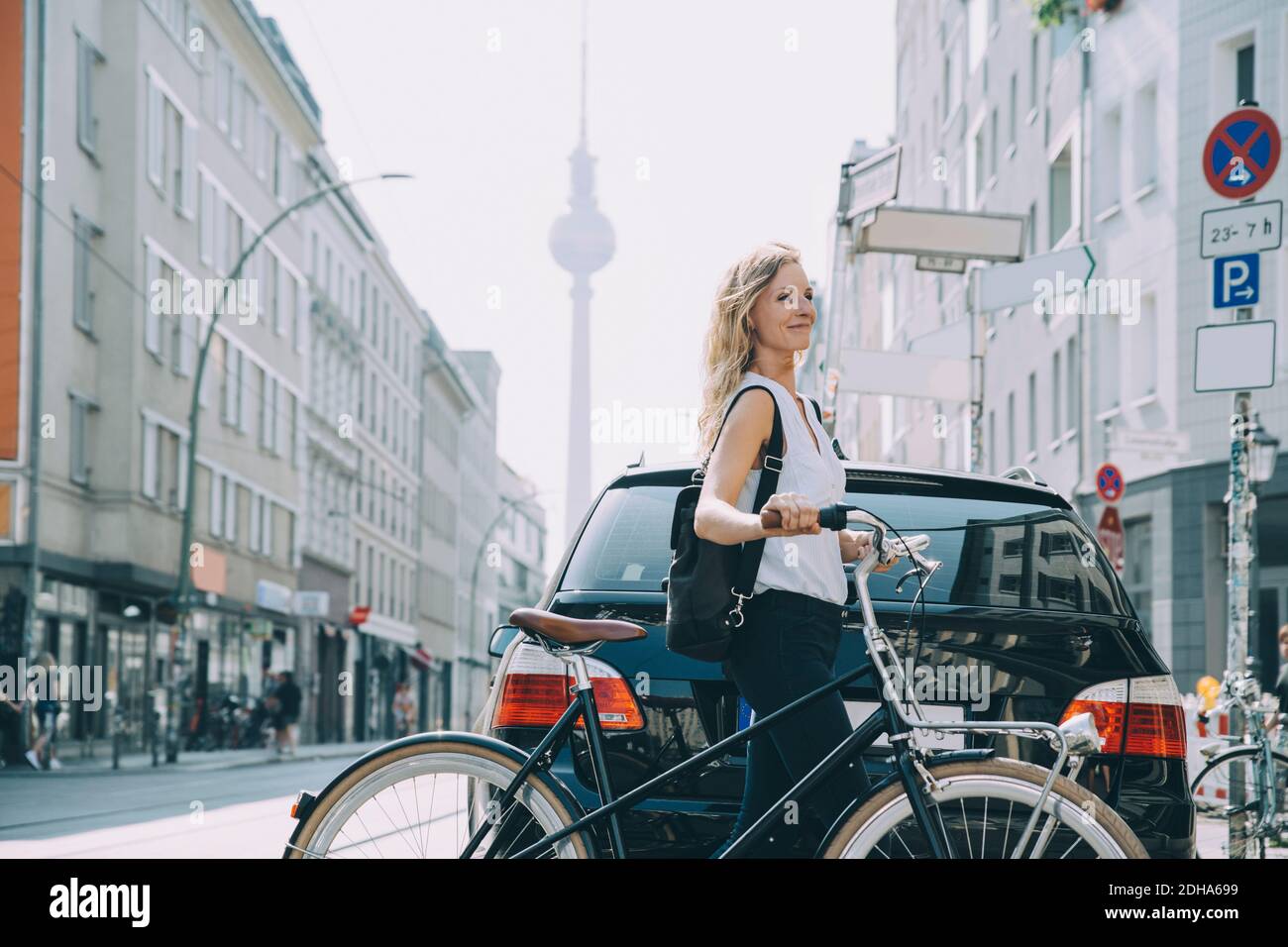 Lächelnde junge Frau mit Rucksack Fahrrad auf der Straße reiten Stadt Stockfoto