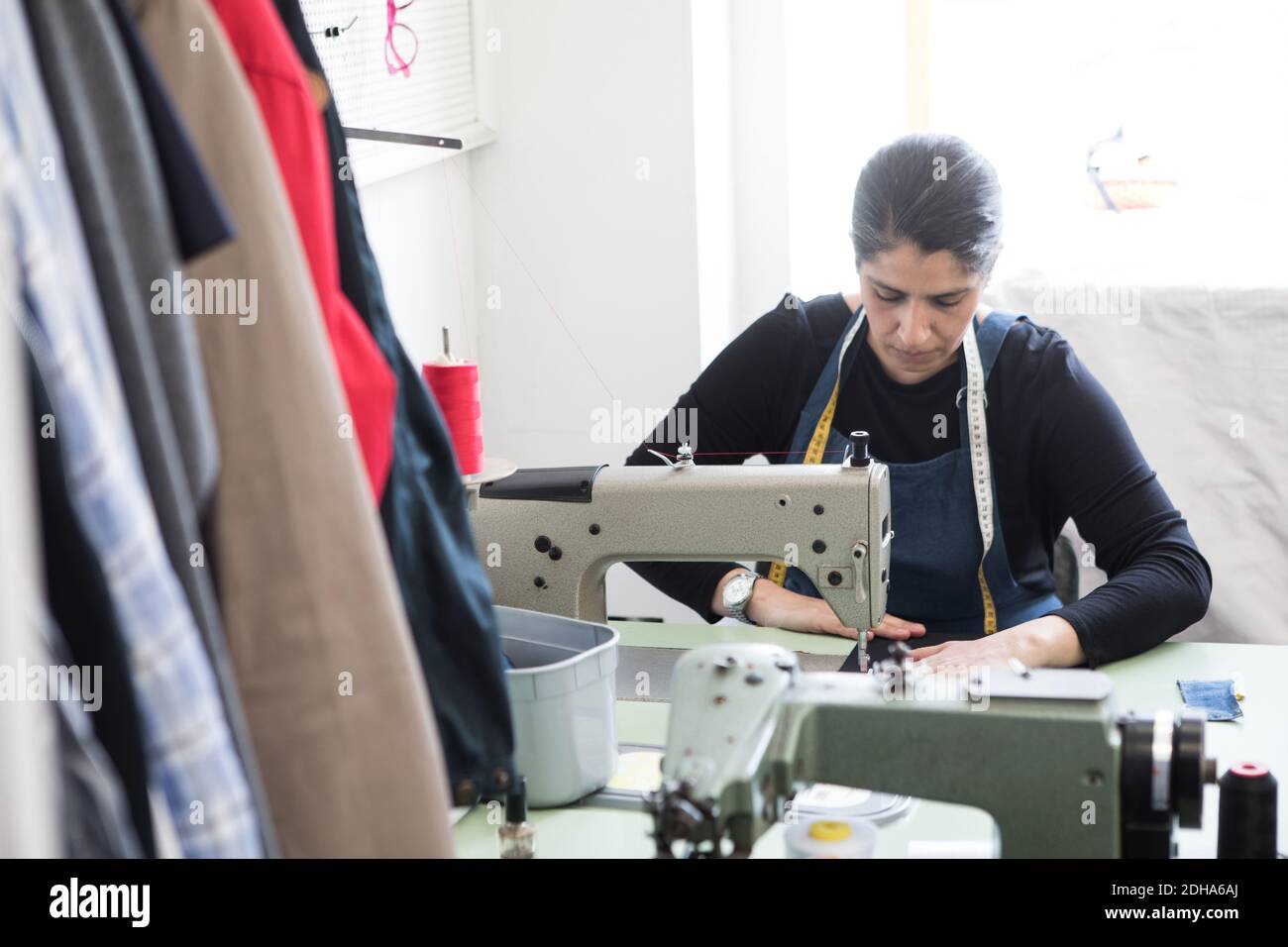 Reife weibliche Schneiderin mit Nähmaschine bei Laundromat Stockfoto