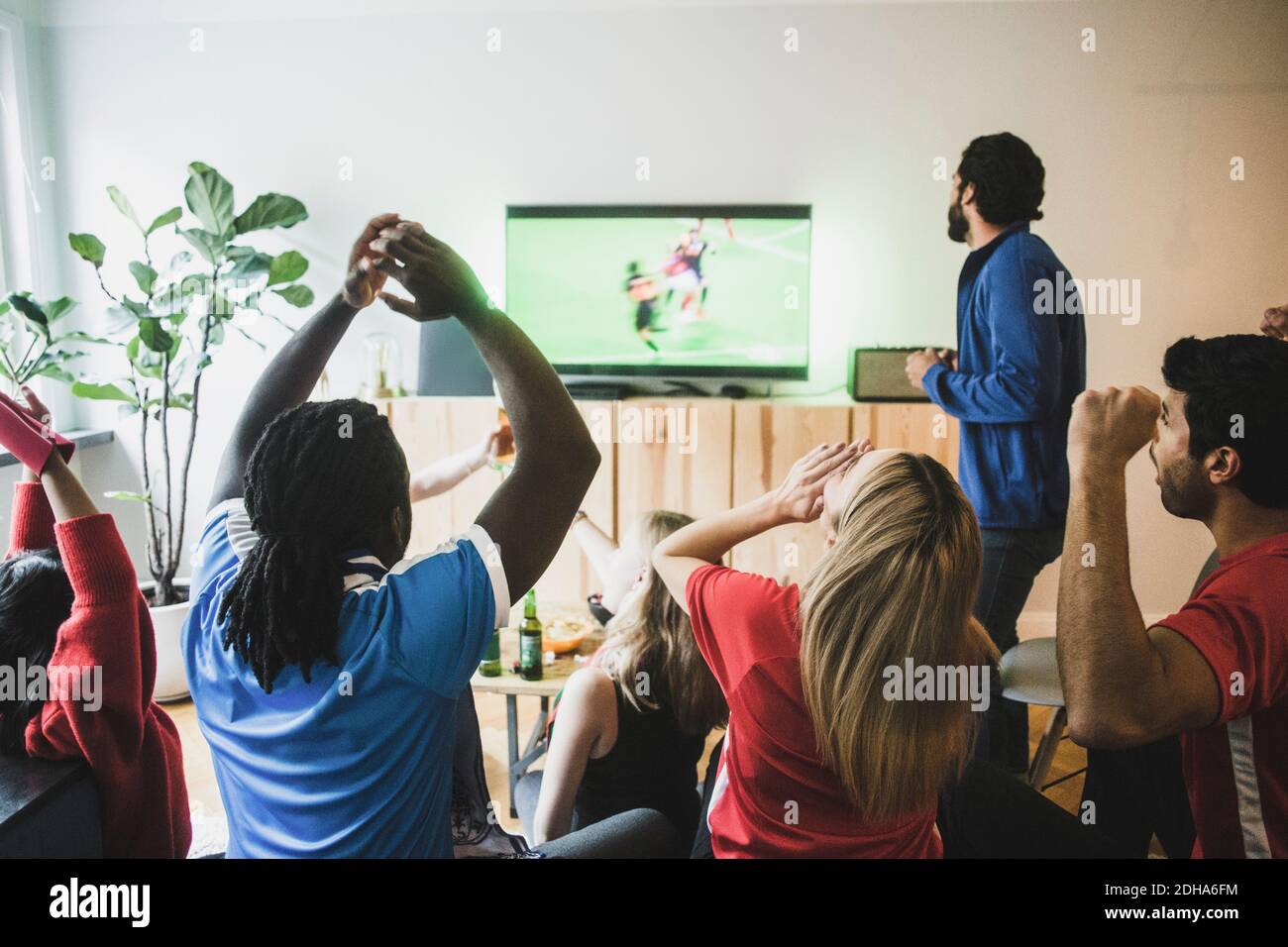 Die Fans jubeln, während sie zu Hause ein Fußballspiel im Fernsehen sehen Stockfoto