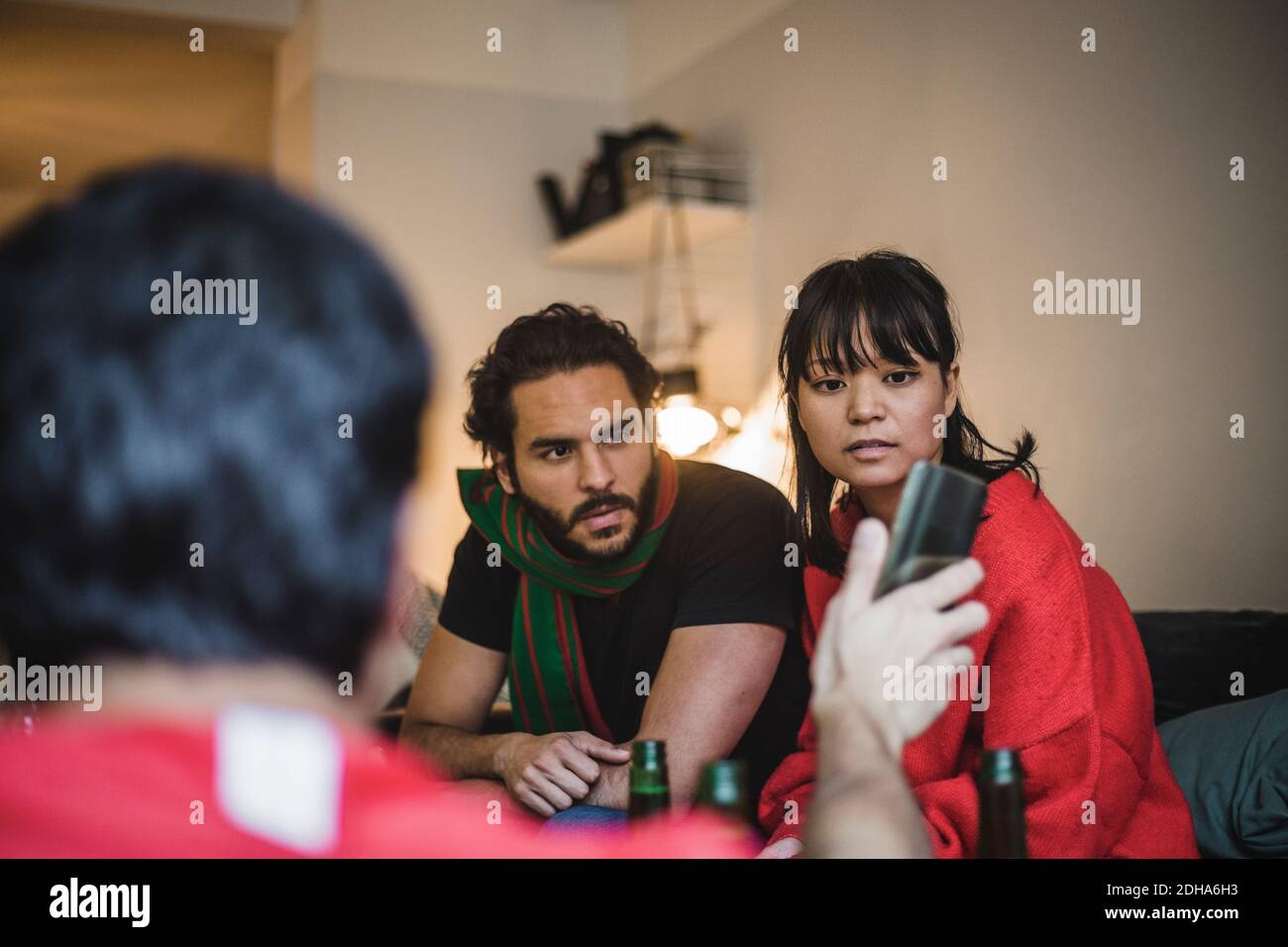 Rückansicht des Mannes, der Freunden das Mobiltelefon zeigt Sitzen auf dem Sofa zu Hause Stockfoto