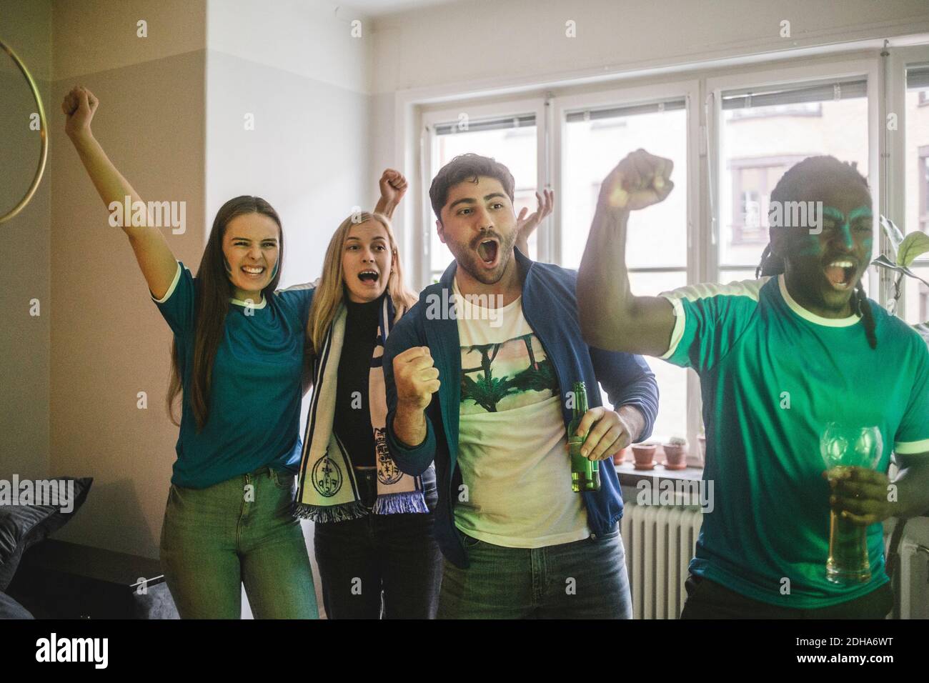 Junge fröhliche Freunde beobachten Fußballspiel, während im Leben stehen Zimmer Stockfoto