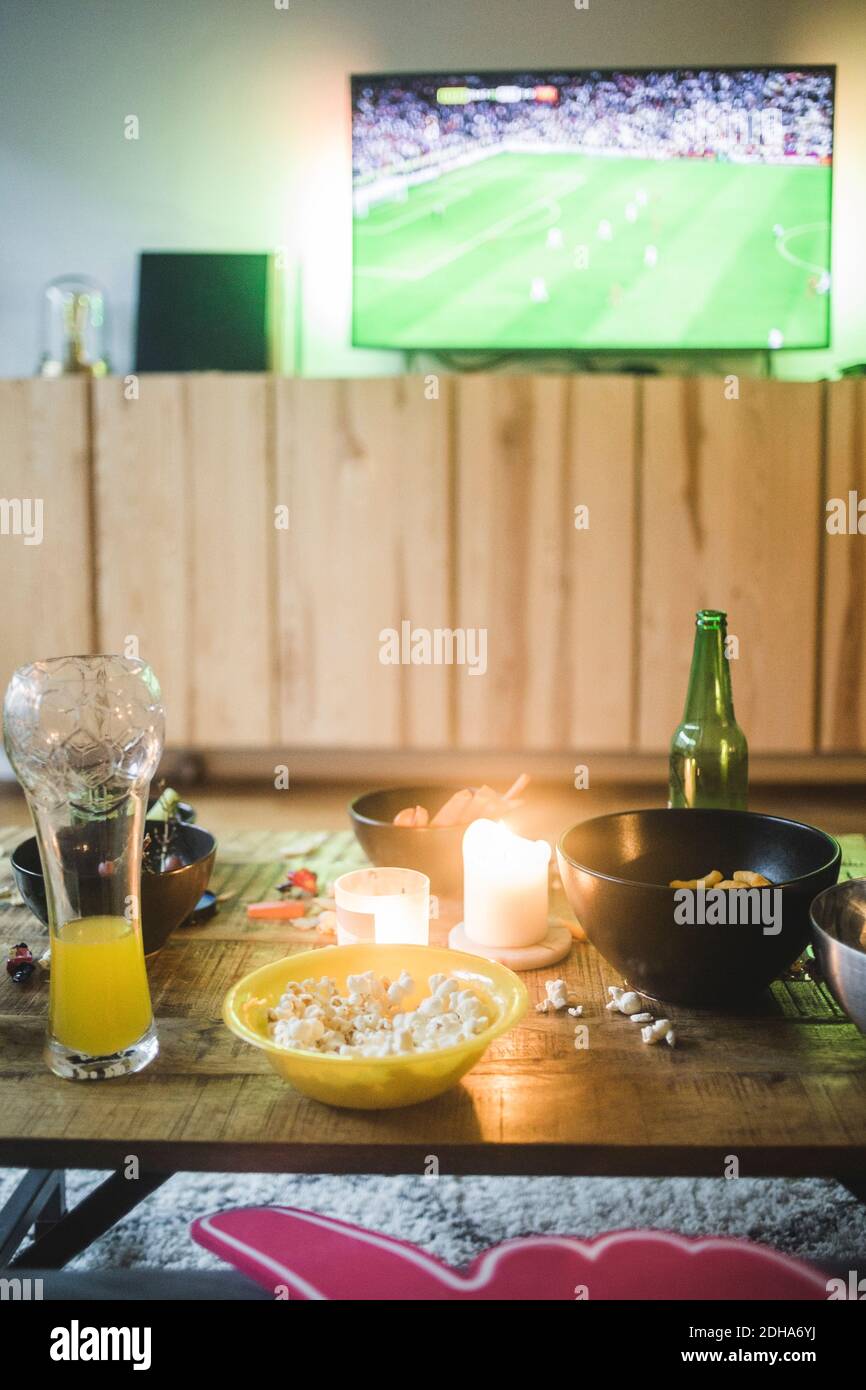 Essen und Trinken auf dem Tisch gegen Fernseher im Wohnzimmer Stockfoto