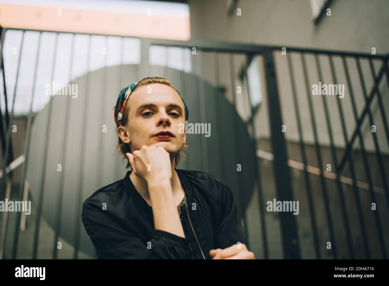 Low-Winkel-Porträt des jungen Mannes sitzt gegen Geländer Stockfoto