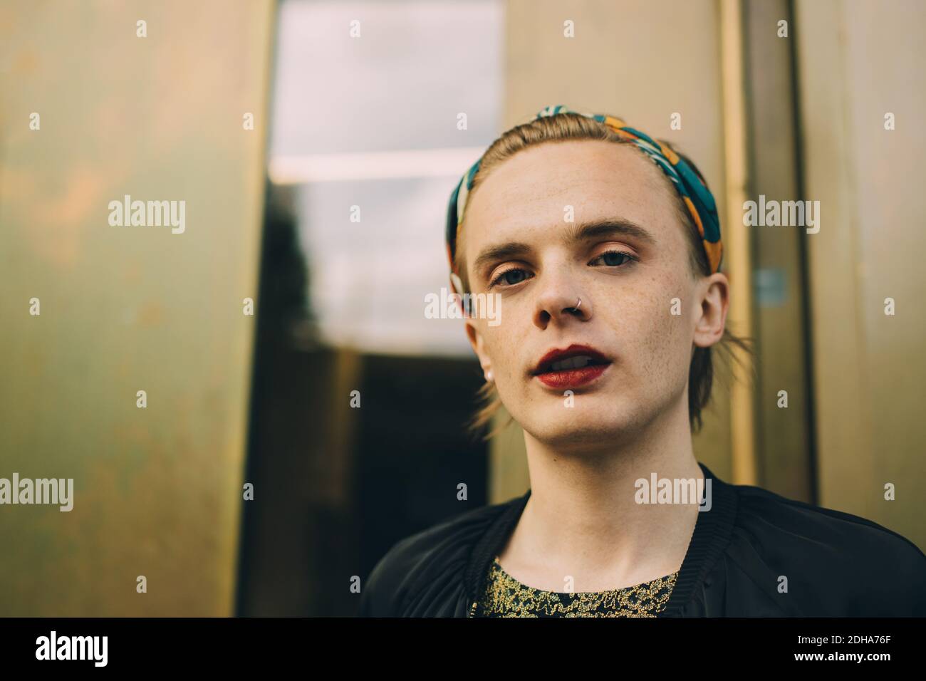 Porträt eines Mannes mit rotem Lippenstift, der gegen die Wand steht Stockfoto