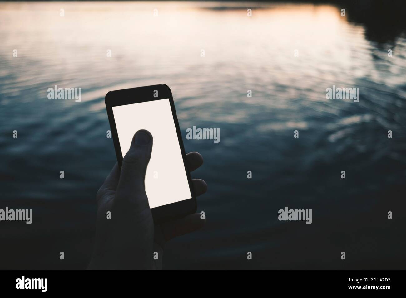 Zugeschnittenes Bild eines Mannes mit Smartphone am See Stockfoto