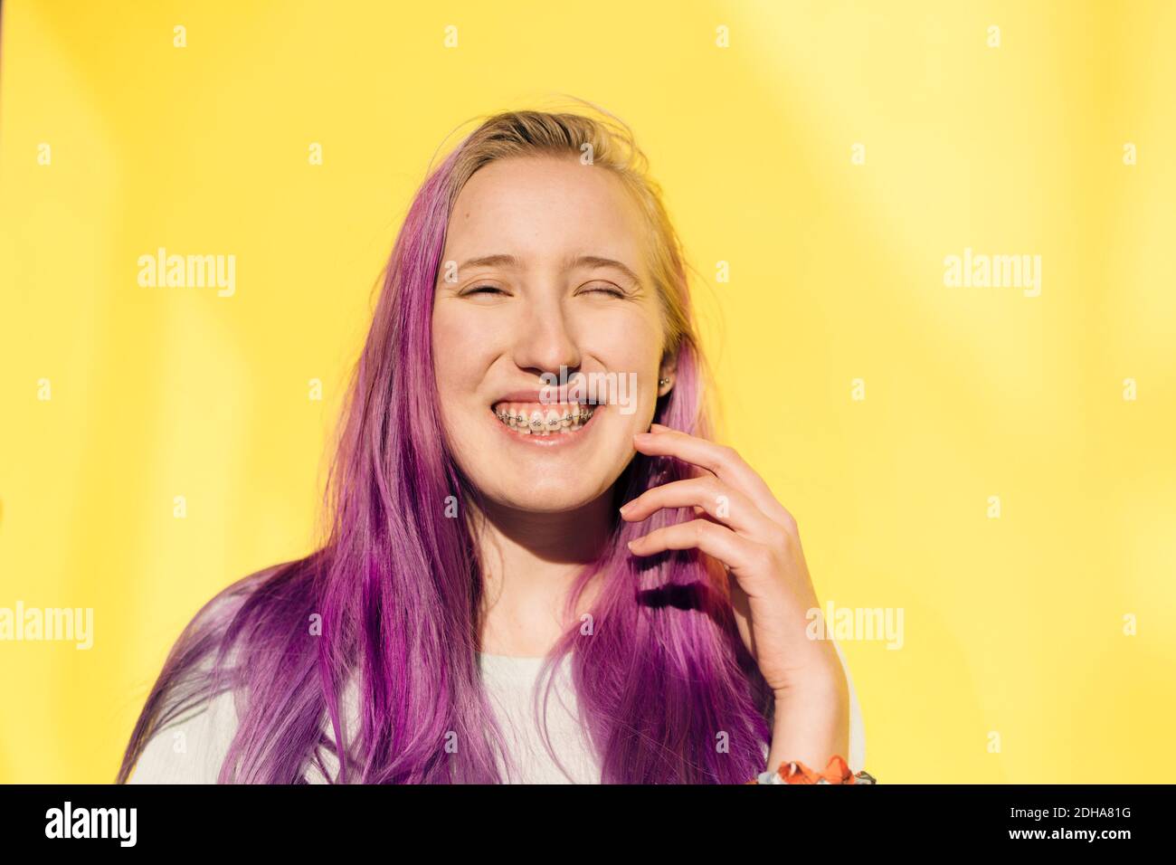 Portrait von lächelndem Teenager-Mädchen, das vor gelbem Hintergrund steht Stockfoto