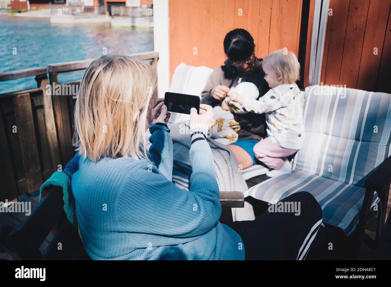 Freund fotografieren Frau spielen mit Kindern über Smartphone an Ferienvilla Stockfoto