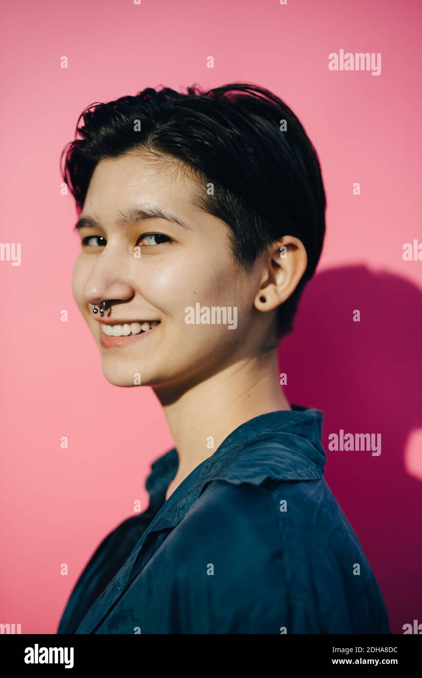 Porträt einer lächelnden jungen Frau vor rosa Hintergrund Stockfoto