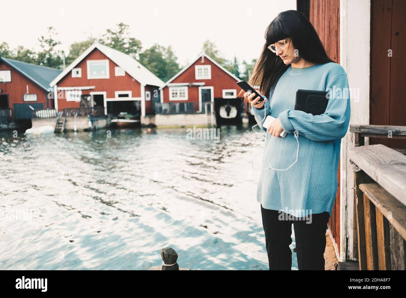 Frau, die Smartphone benutzt, während sie am See steht Stockfoto