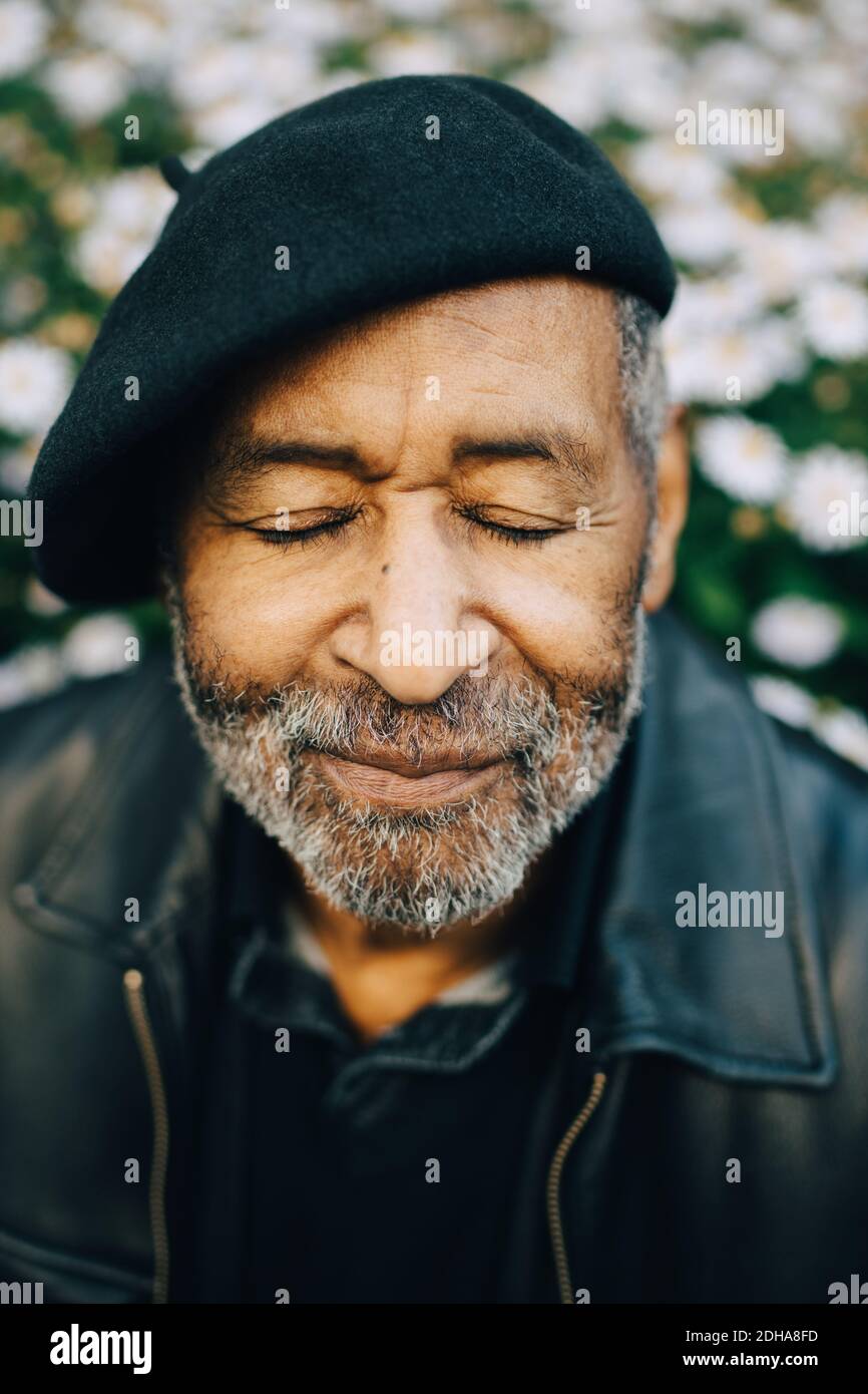Älterer Mann mit geschlossenen Augen gegen Blumen Stockfoto