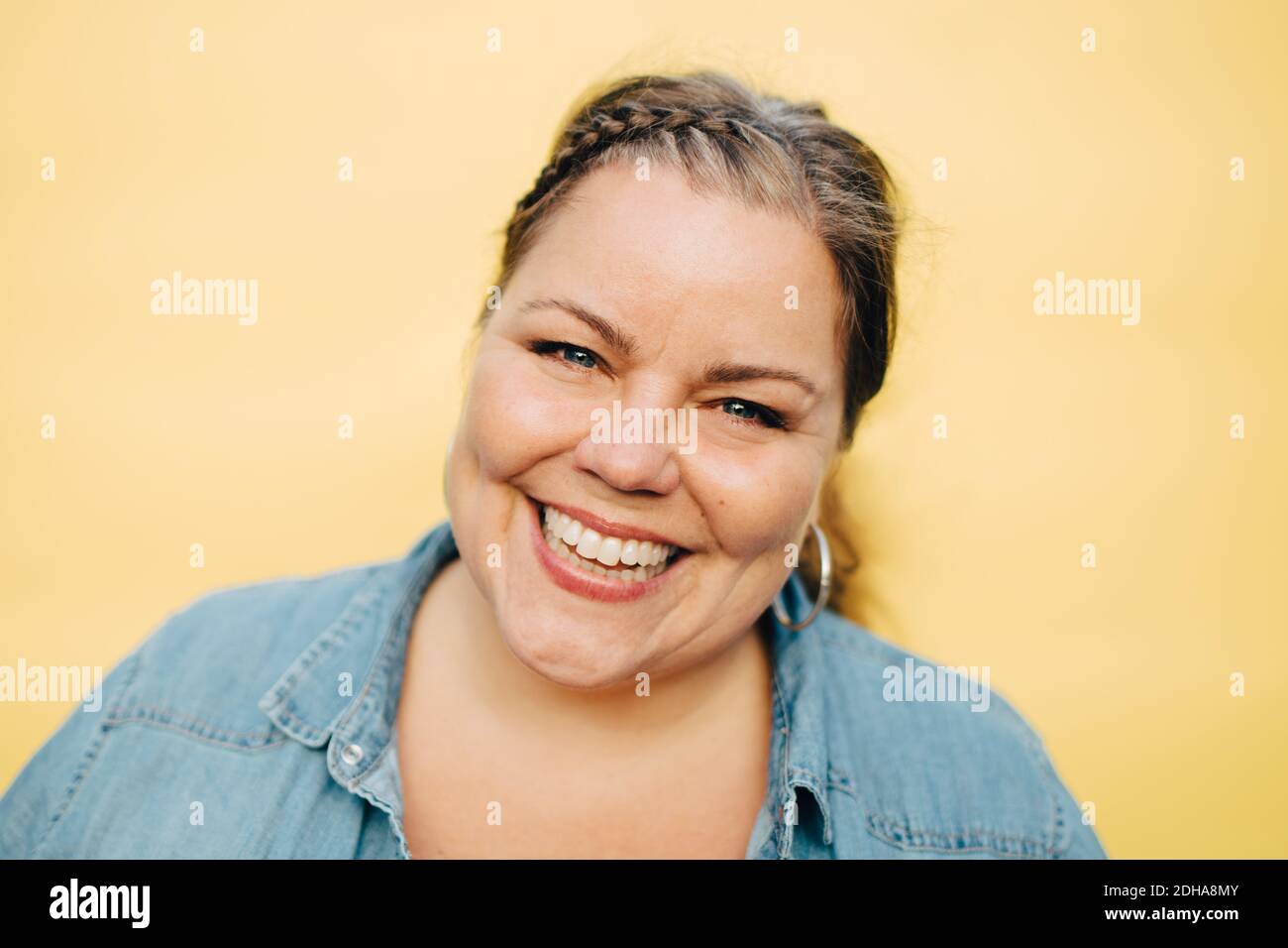 Porträt von lächelnden reifen Frau vor gelbem Hintergrund Stockfoto