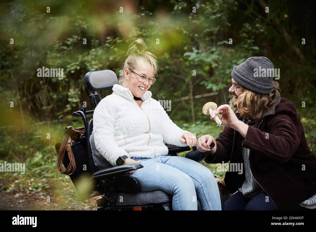 Männliche Hausmeister zeigt Pilz zu behinderten Frau im Rollstuhl an Wald Stockfoto