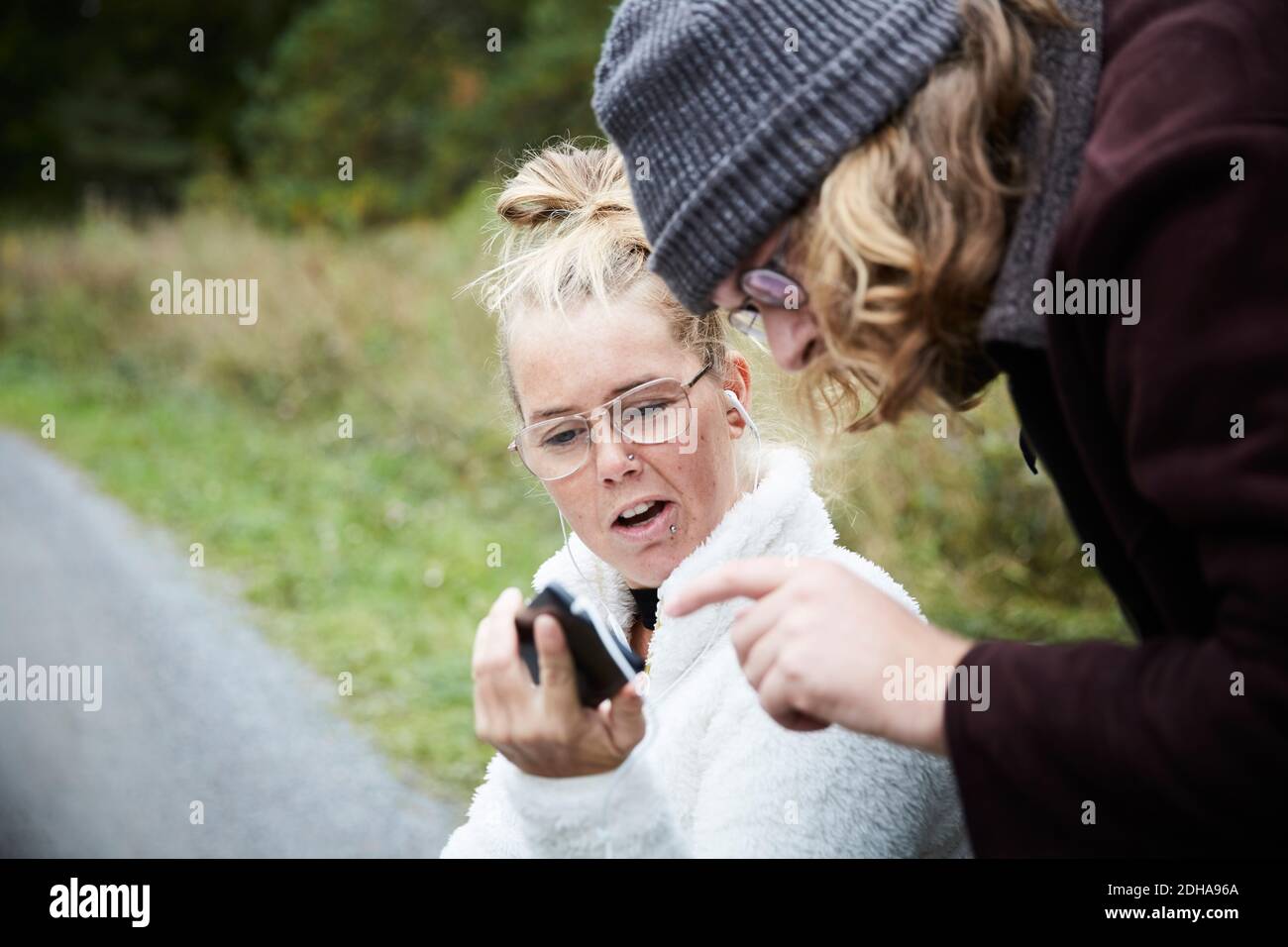 Junge männliche Hausmeister und behinderte Frau mit Handy im Freien Stockfoto