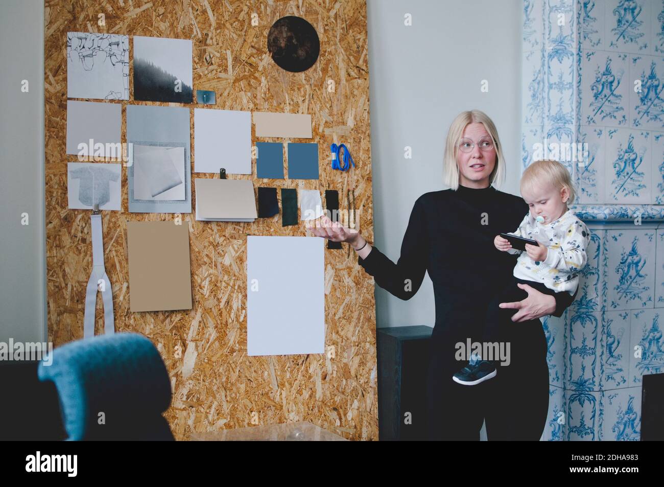 Mittlere Erwachsene Geschäftsfrau trägt Baby Mädchen, während die Präsentation in Kreatives Büro Stockfoto