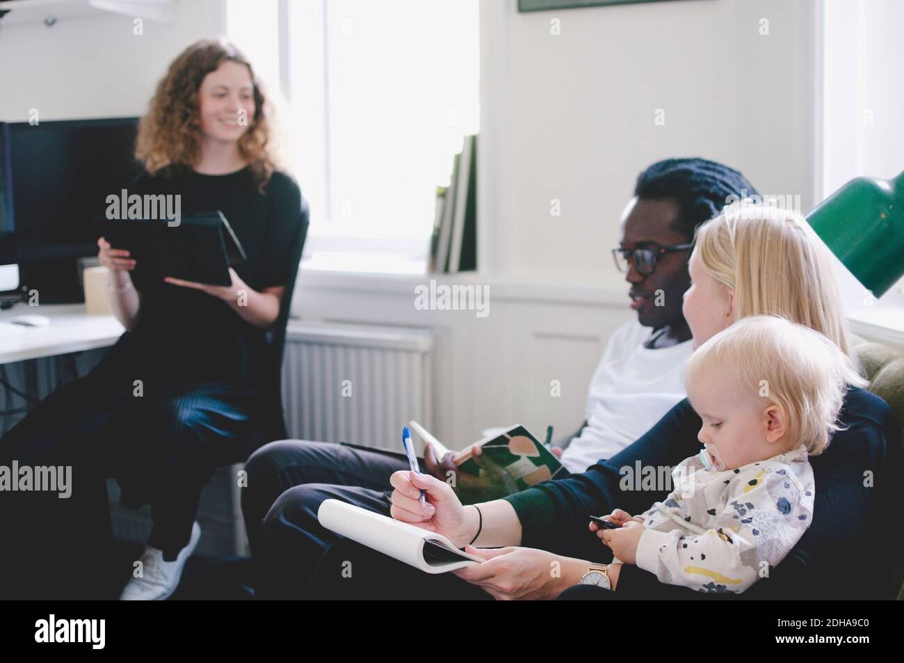 Arbeiten Mutter mit Baby diskutieren mit Kollegen im kreativen Büro Stockfoto