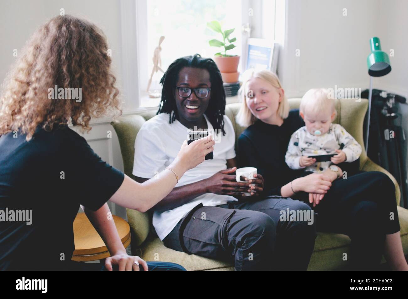 Junge Geschäftsfrau, die Kollegen im Kreativbüro das Mobiltelefon zeigt Stockfoto